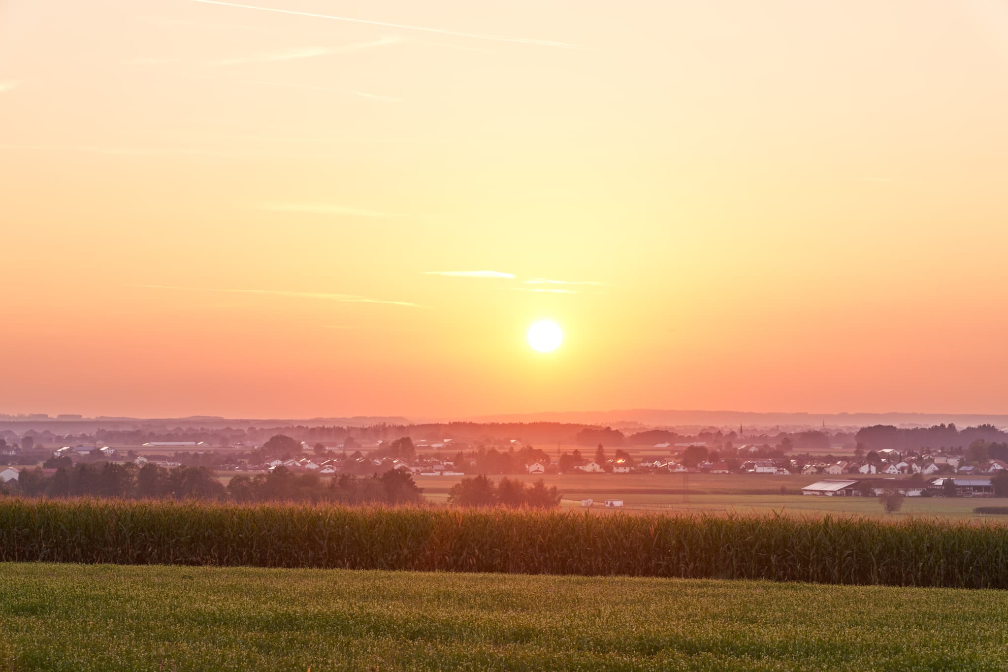 Sonnenuntergang über Landschaft bei Unterneukirchen im Landkreis Altötting, Oberbayern. Aussicht auf Felder und Dorf im Inn-Salzach-Gebiet, Deutschland.