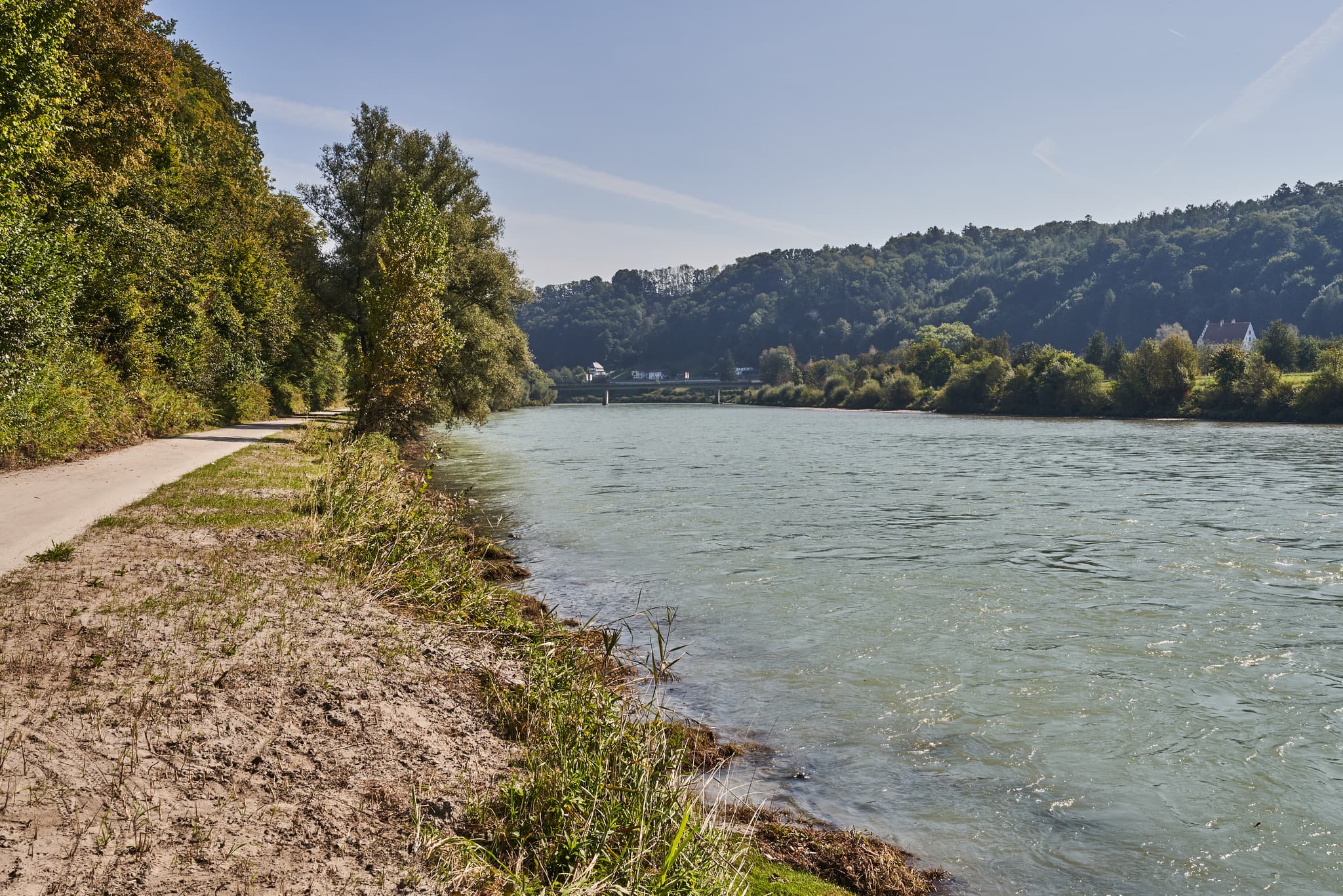 Weg am Ufer der Salzach bei Burghausen Richtung Raitenhaslach. Flusslandschaft im Landkreis Altötting, Oberbayern, Deutschland. Grüne Ufer und bewaldete Hügel.