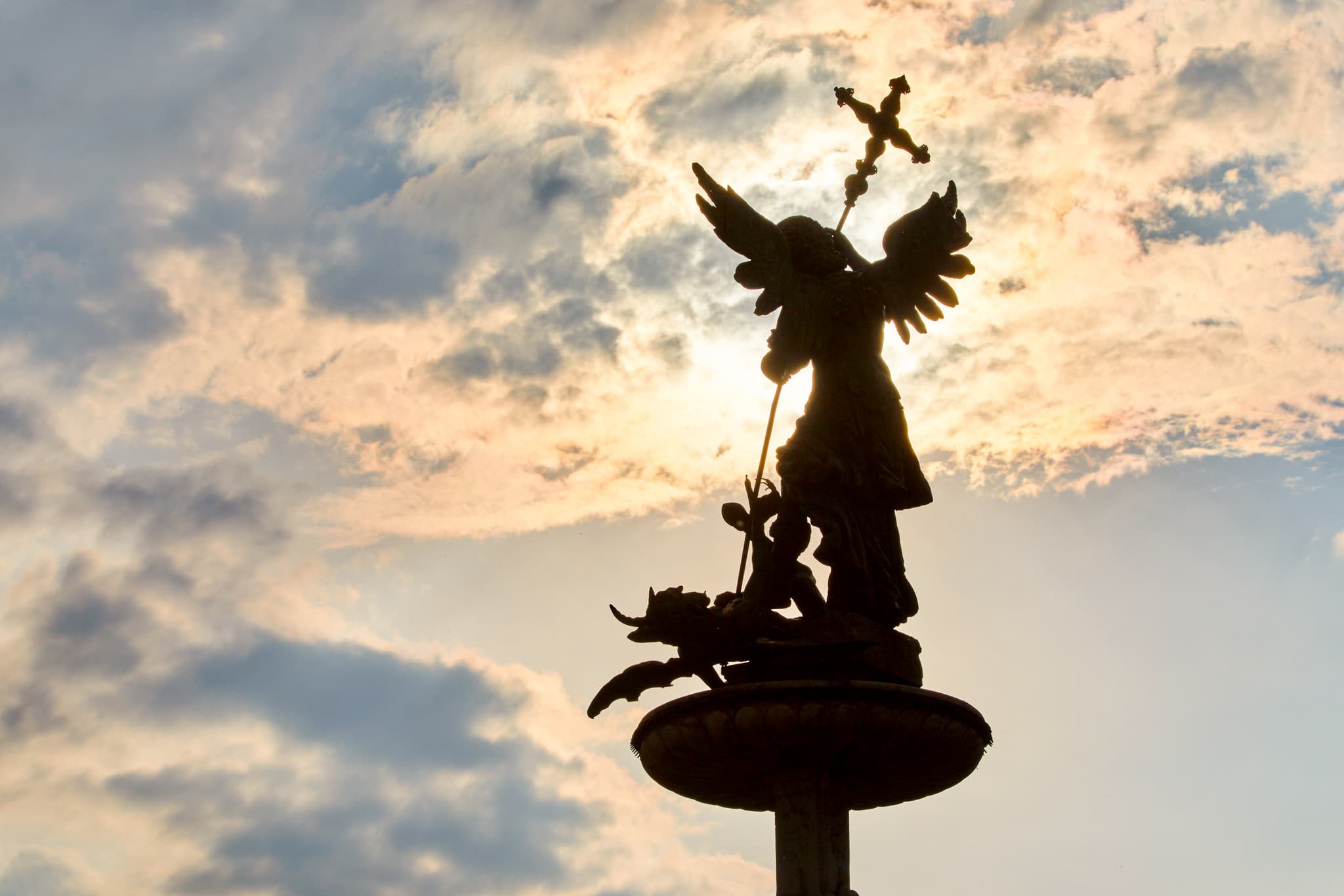 Silhouette einer Engel-Statue im Gegenlicht, aufgenommen in Reichersberg, Oberösterreich. Das Denkmal befindet sich im Bezirk Ried, Österreich.