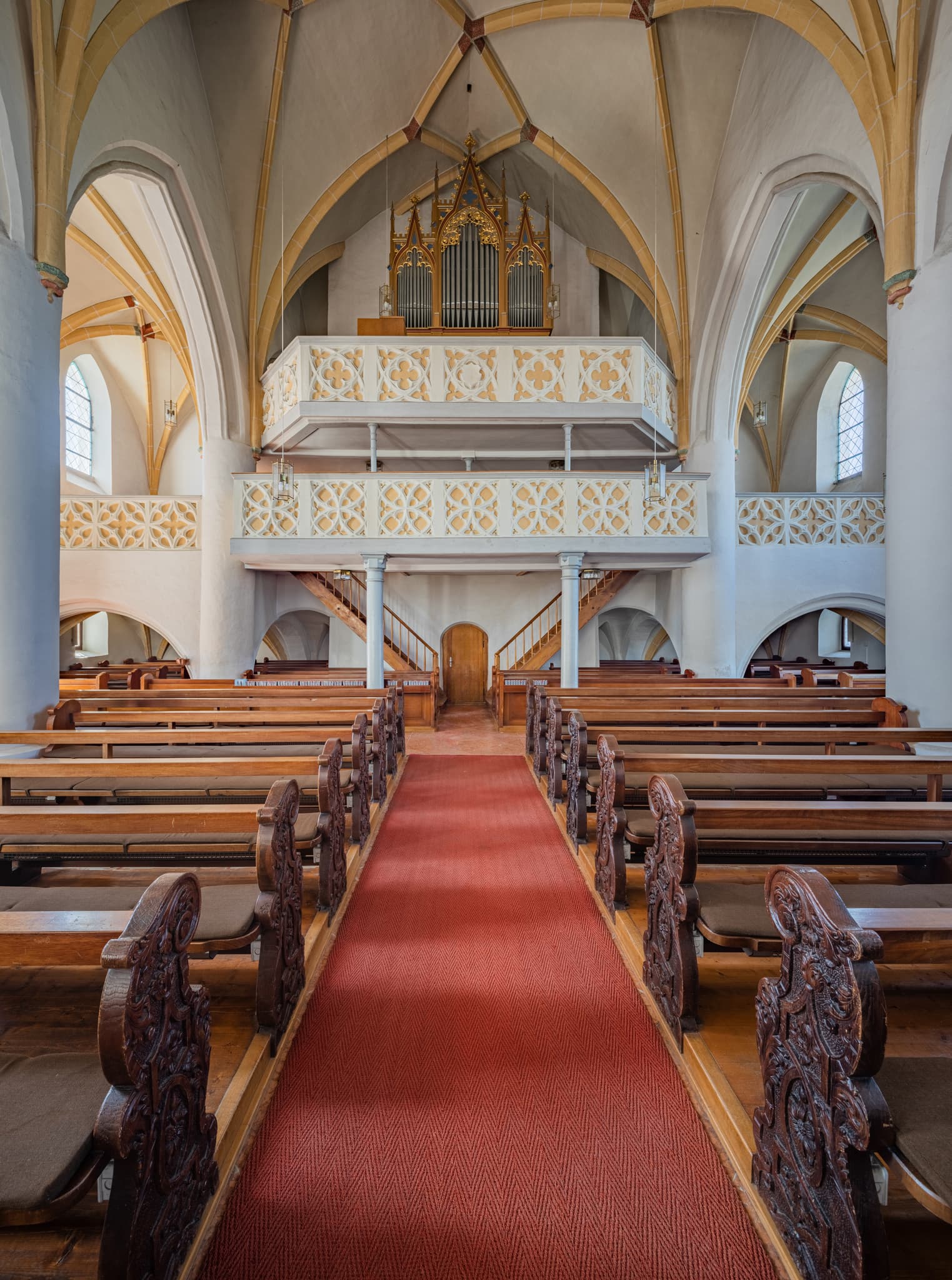 Innenansicht der Kirche in Unterdietfurt, Landkreis Rottal-Inn, Niederbayern, Deutschland. Das Bild zeigt den Mittelgang mit Holzbänken und die Orgel.