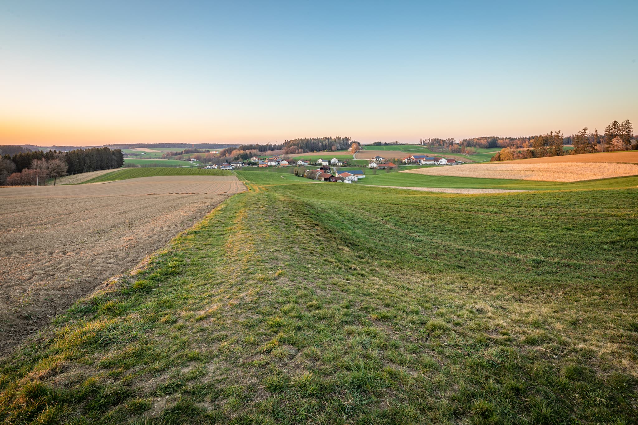 Landschaft bei Holzham, Reischach, Landkreis Altötting, Oberbayern, Deutschland. Weite Felder und Dorfansicht im Holzland vom Feldkreuz.