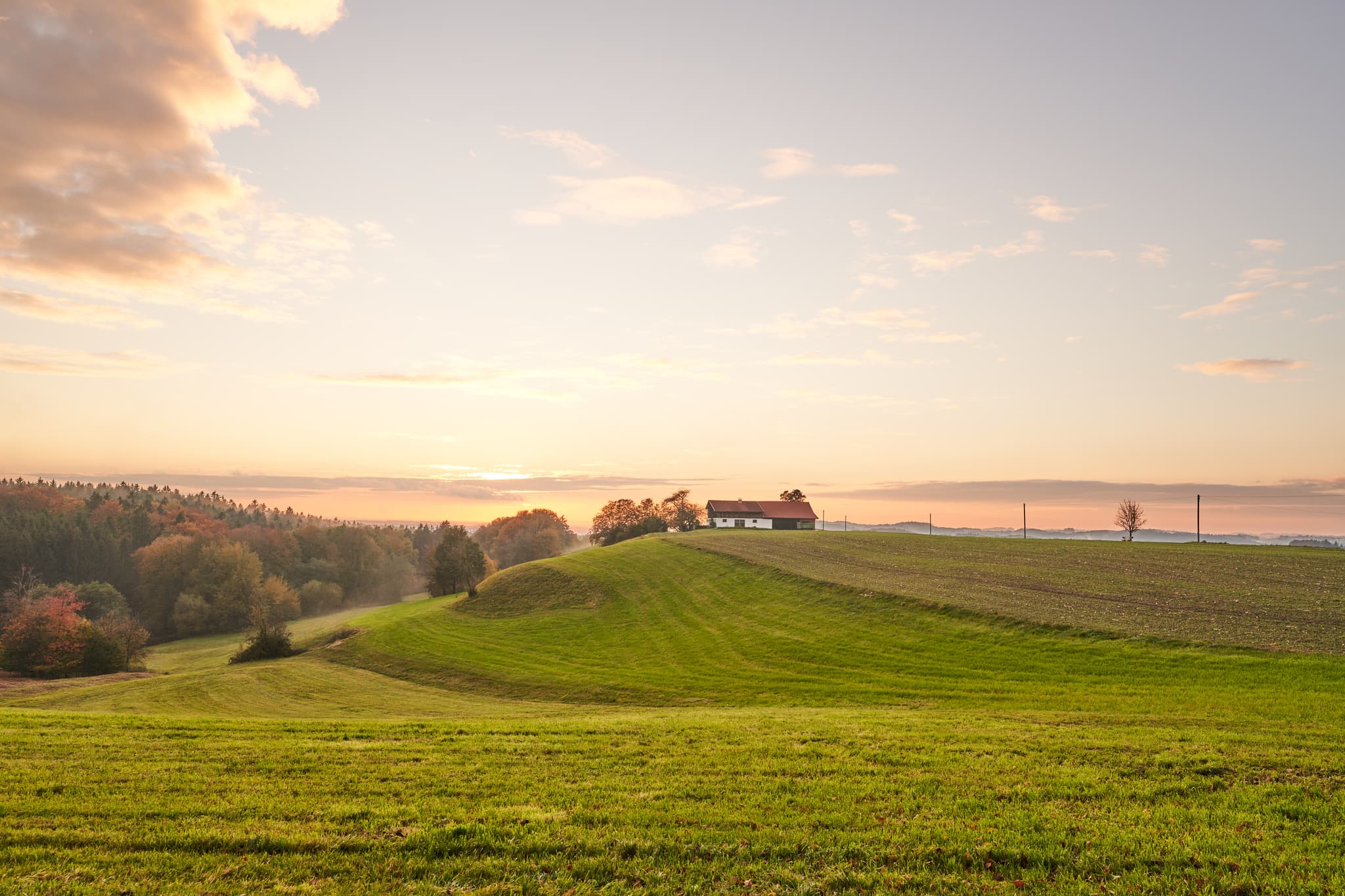 Herbstliche Hügellandschaft mit Hofstelle, Feldern und Wald bei Berg, Perach, Altötting, Oberbayern, Inn-Salzach, Deutschland. Eine ruhige Landschaftsaufnahme.