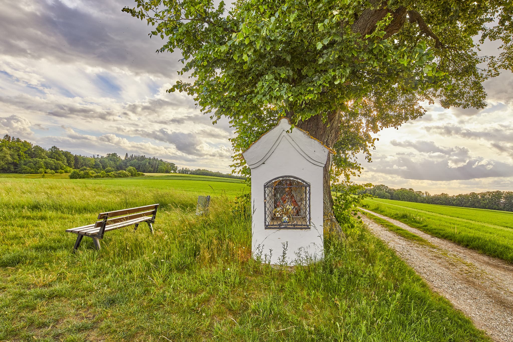 Bildstock an Feldweg bei Wald, Garching, Landkreis Altötting. Landschaft Oberbayerns, Region Inn-Salzach, Deutschland mit Feldern und Baum.
