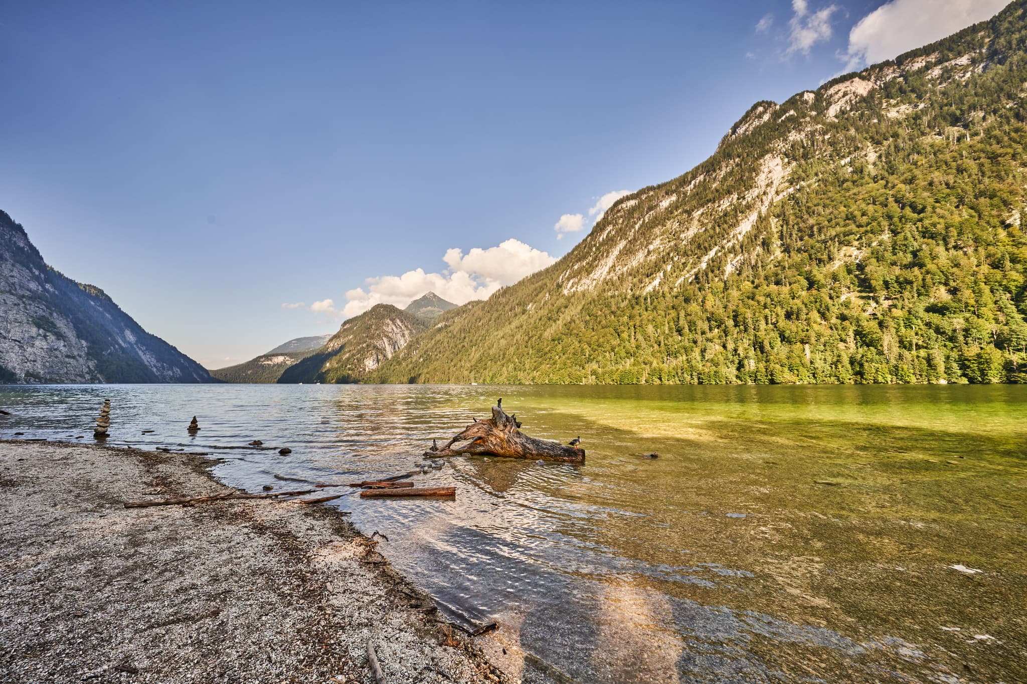 Königssee in Schönau, Berchtesgadener Land, Oberbayern, Nationalpark Berchtesgadener Alpen, Deutschland, mit klarem Wasser, bewaldeten Bergen und Strand.