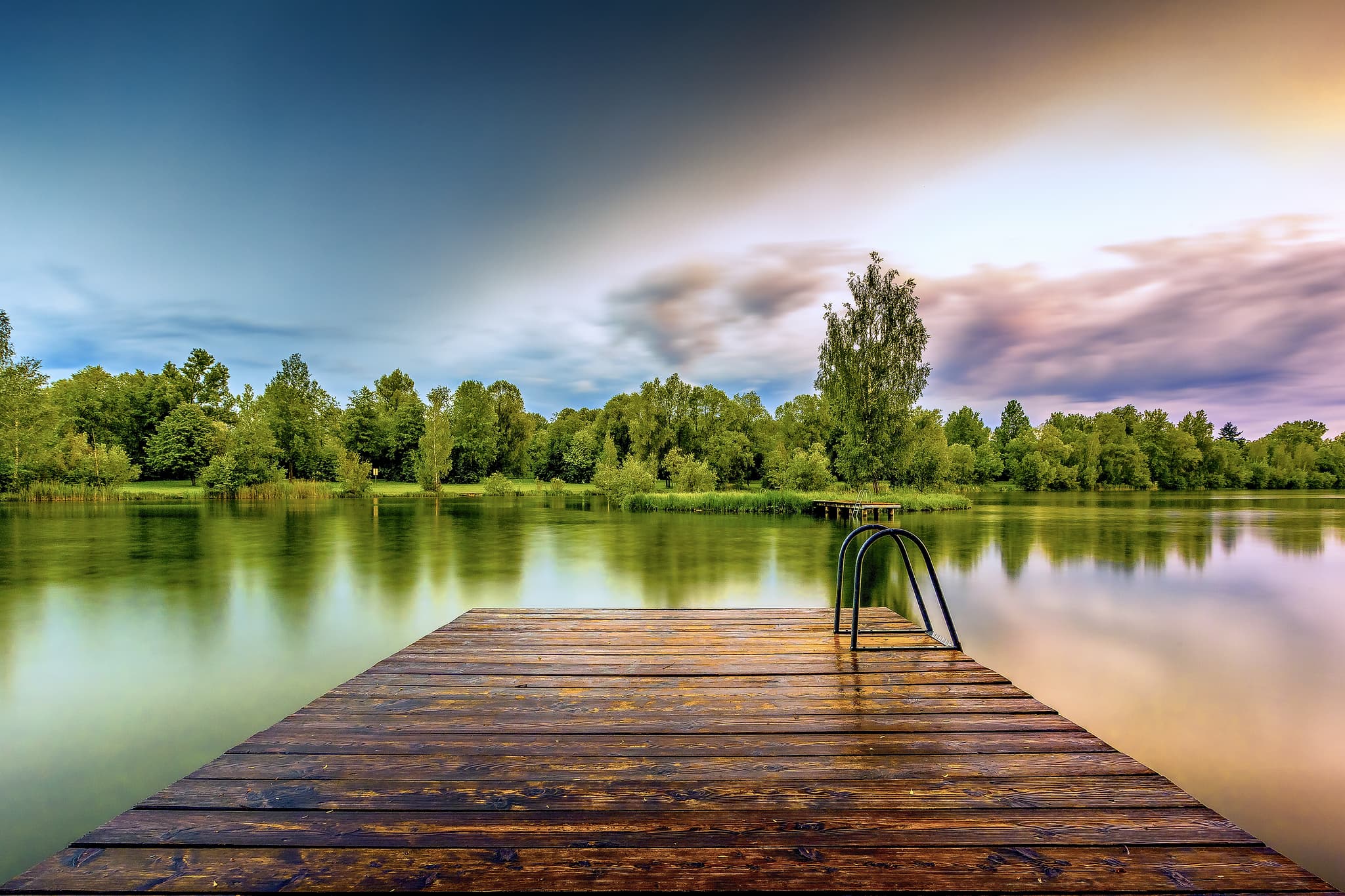 Idyllischer Holzsteg am Badesee Steg gerade in Perach, Altötting, Oberbayern. Ruhige Wasserfläche, grüne Ufer im Inn-Salzach Gebiet, Deutschland gelegen.