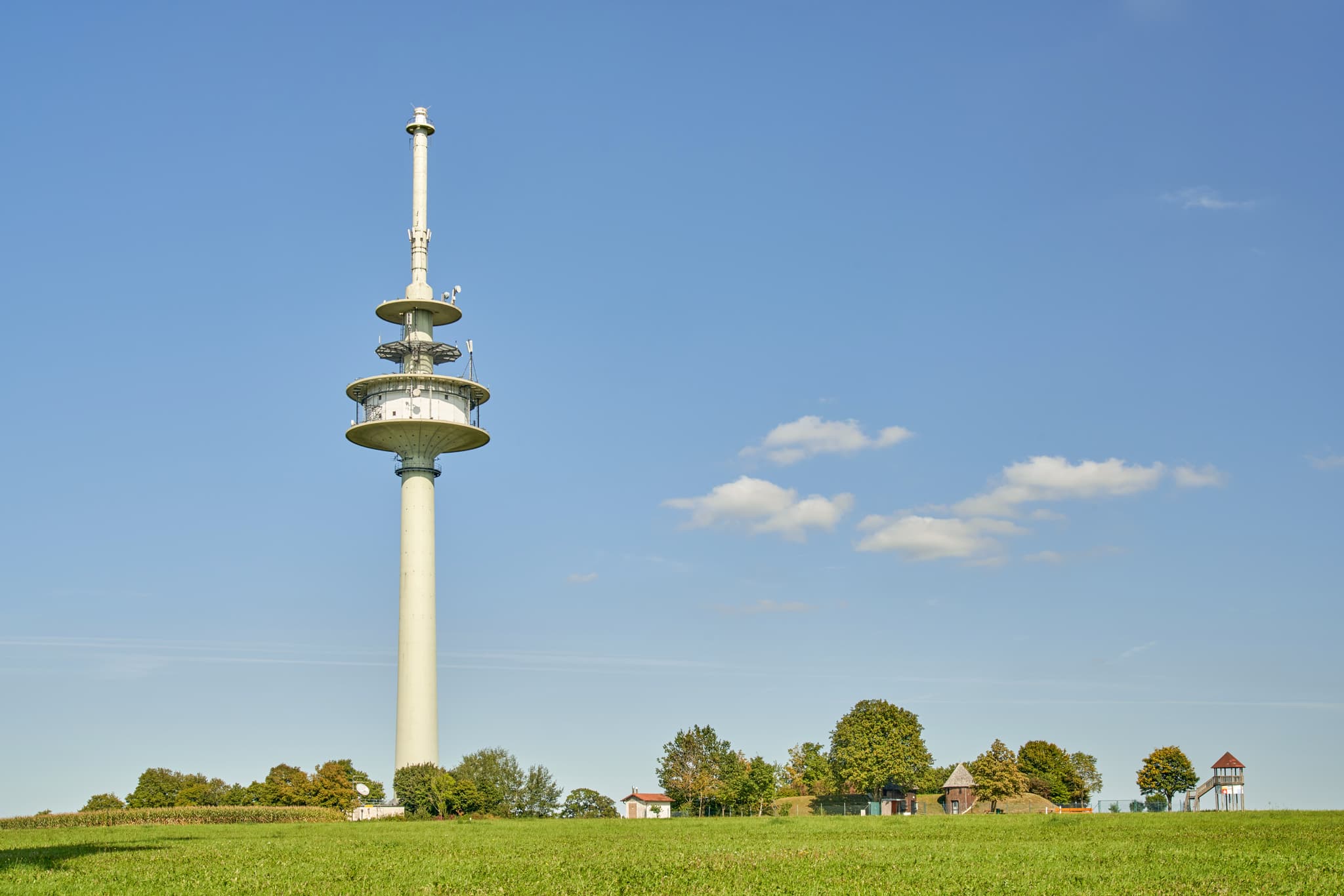 Funkturm in ländlicher Landschaft bei Schnaitsee, Landkreis Traunstein, Oberbayern, Deutschland, zeigt weite Grünflächen unter blauem Himmel.