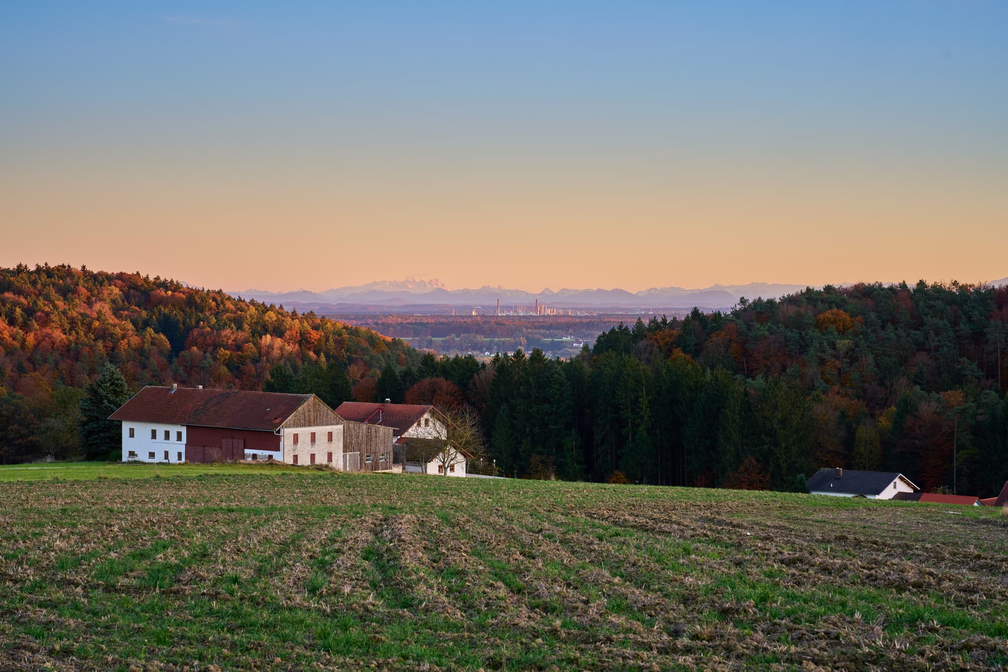 Herbstlandschaft in Pfaffenberg, Erlbach, Altötting. Weitblick über Felder, Bauernhöfe. Inn-Salzach, Oberbayern, zeigt Alpenkette und ferne Industrieanlagen.