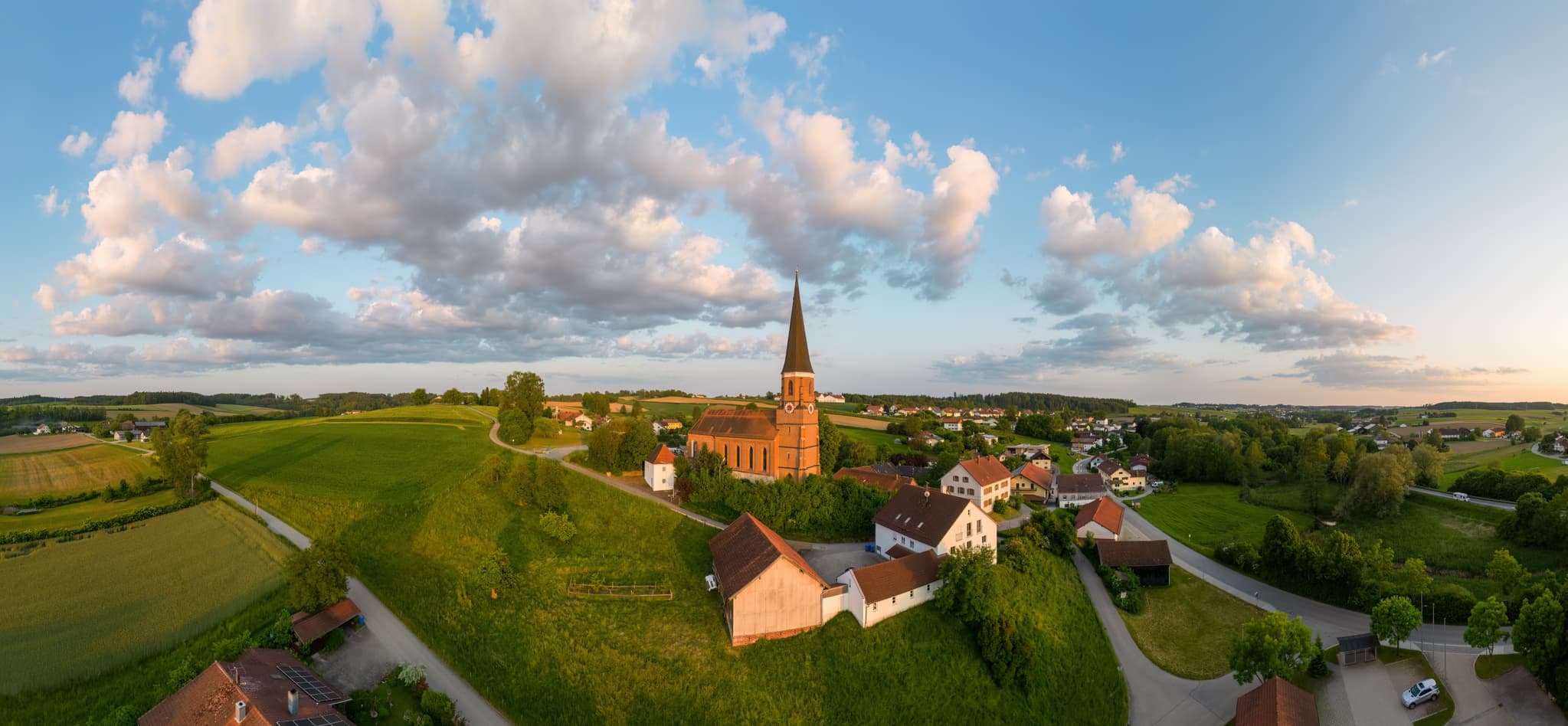 Pfarrkirche St. Rupert in Hirschhorn, Wurmannsquick, Rottal-Inn, Niederbayern. Ländliche Szenerie im Holzland, Deutschland, mit Feldern und Häusern.