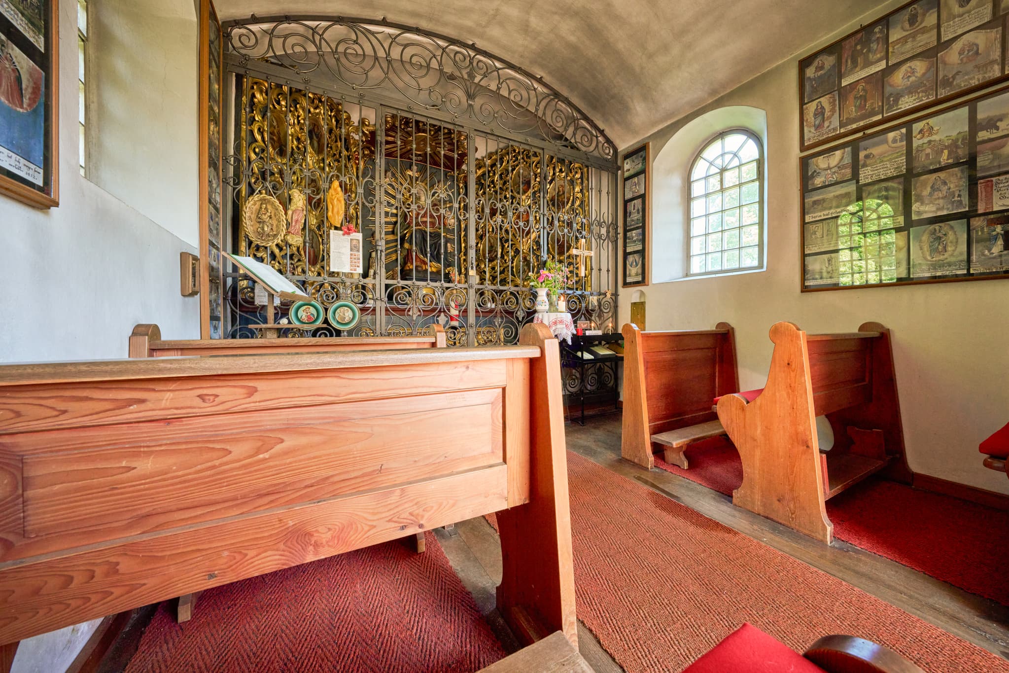 Blick in die Kronwidl Kapelle in Ecksberg Altmühldorf, Mühldorf am Inn, Oberbayern. Die Kapelle zeigt Holzbänke, ein Altar-Gitter und Wandbilder im Innenraum.