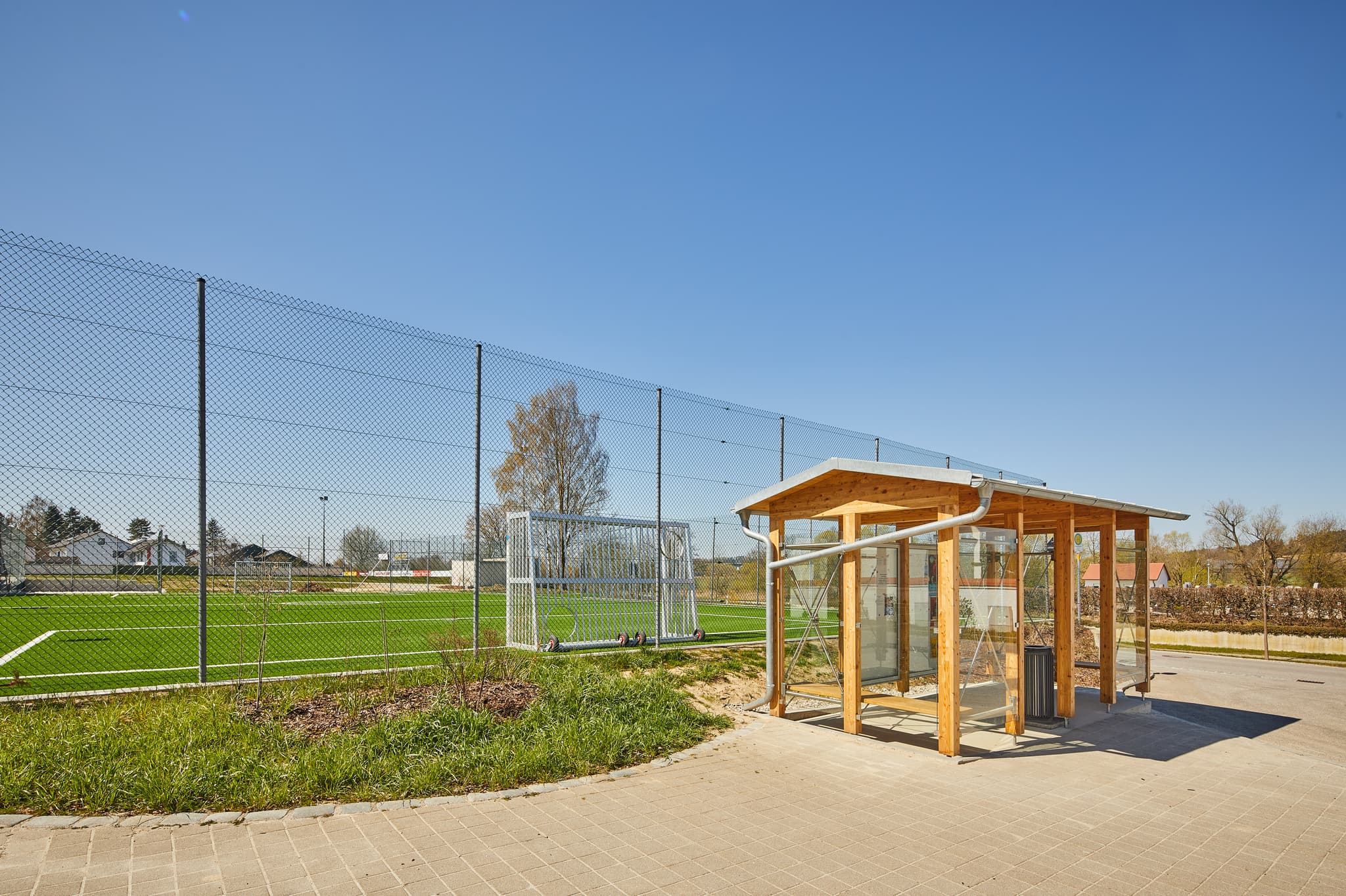 Moderne Bushaltestelle in Unterdietfurt, Rottal-Inn, Niederbayern, Deutschland. Gelegen im Holzland. Das Bild zeigt die Haltestelle neben einem Sportplatz.