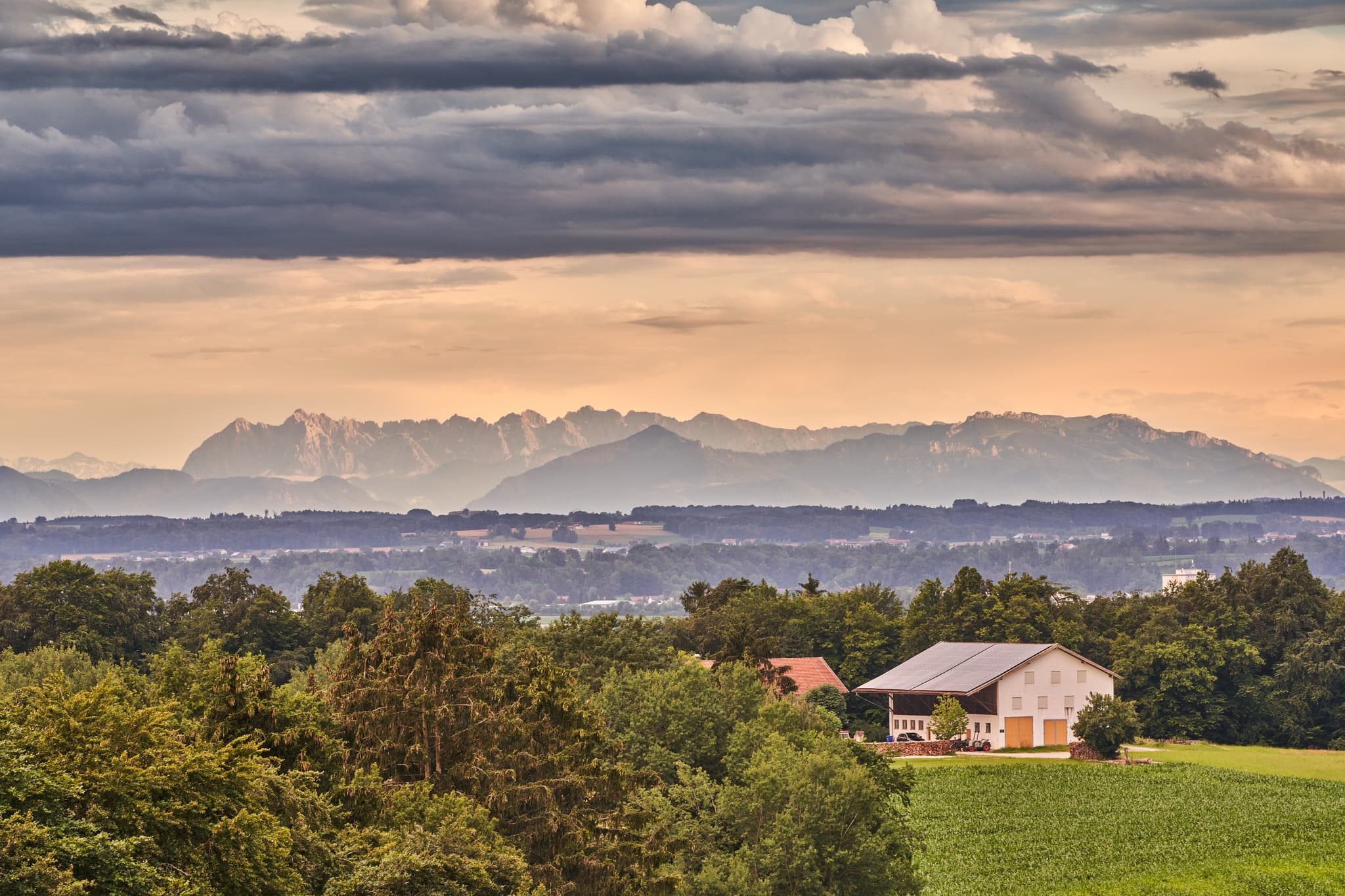 Friesing, Reischach, Altötting, Oberbayern, Inn-Salzach, Deutschland. Ländliche Szene mit Feldern, Wäldern, Bauernhof und Alpen. Himmel bewölkt.