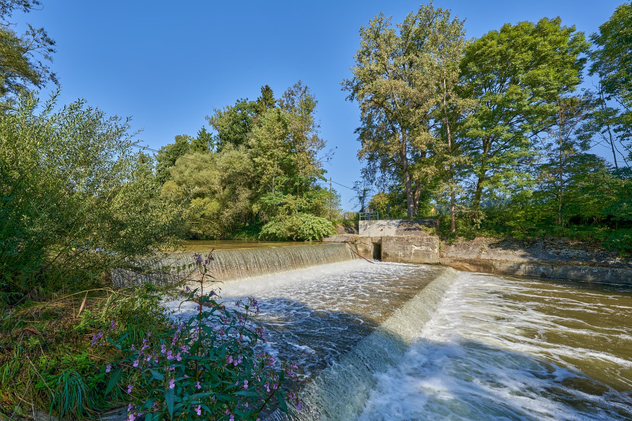 Isen Wasserfall in Winhöring, Altötting, Oberbayern, Deutschland. Ansicht der Wehranlage und umgebender Vegetation. Landschaft in Inn-Salzach.
