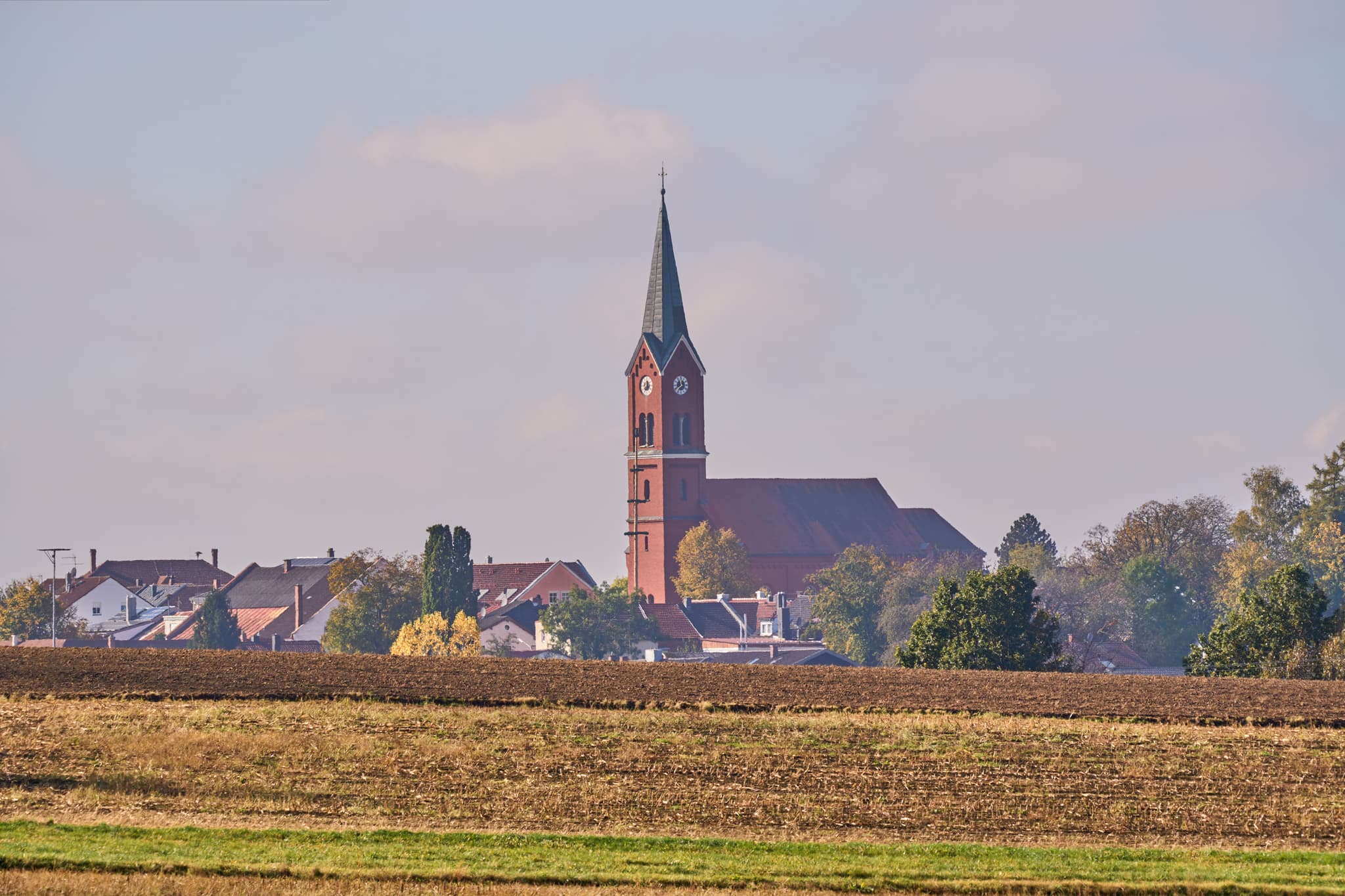 Ländliche Ortsansicht von Wurmannsquick, Rottal-Inn, Niederbayern, Deutschland. Zeigt die Pfarrkirche St. Andreas und Häuser mit Feldern im Holzland.