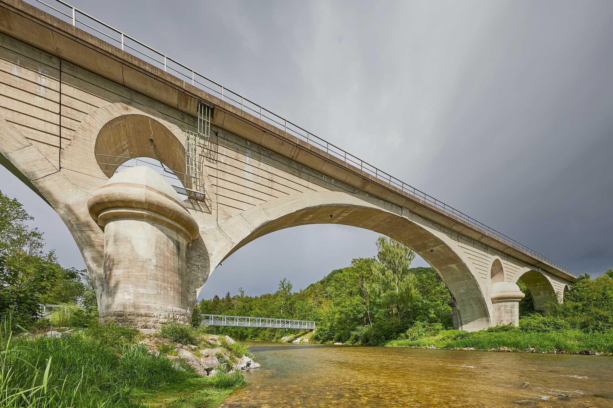 Die Eisenbahnbrücke über die Alz bei Garching, Altötting, Oberbayern, Deutschland, Region Inn-Salzach. Eine solide Betonbogenbrücke überquert den Fluss.