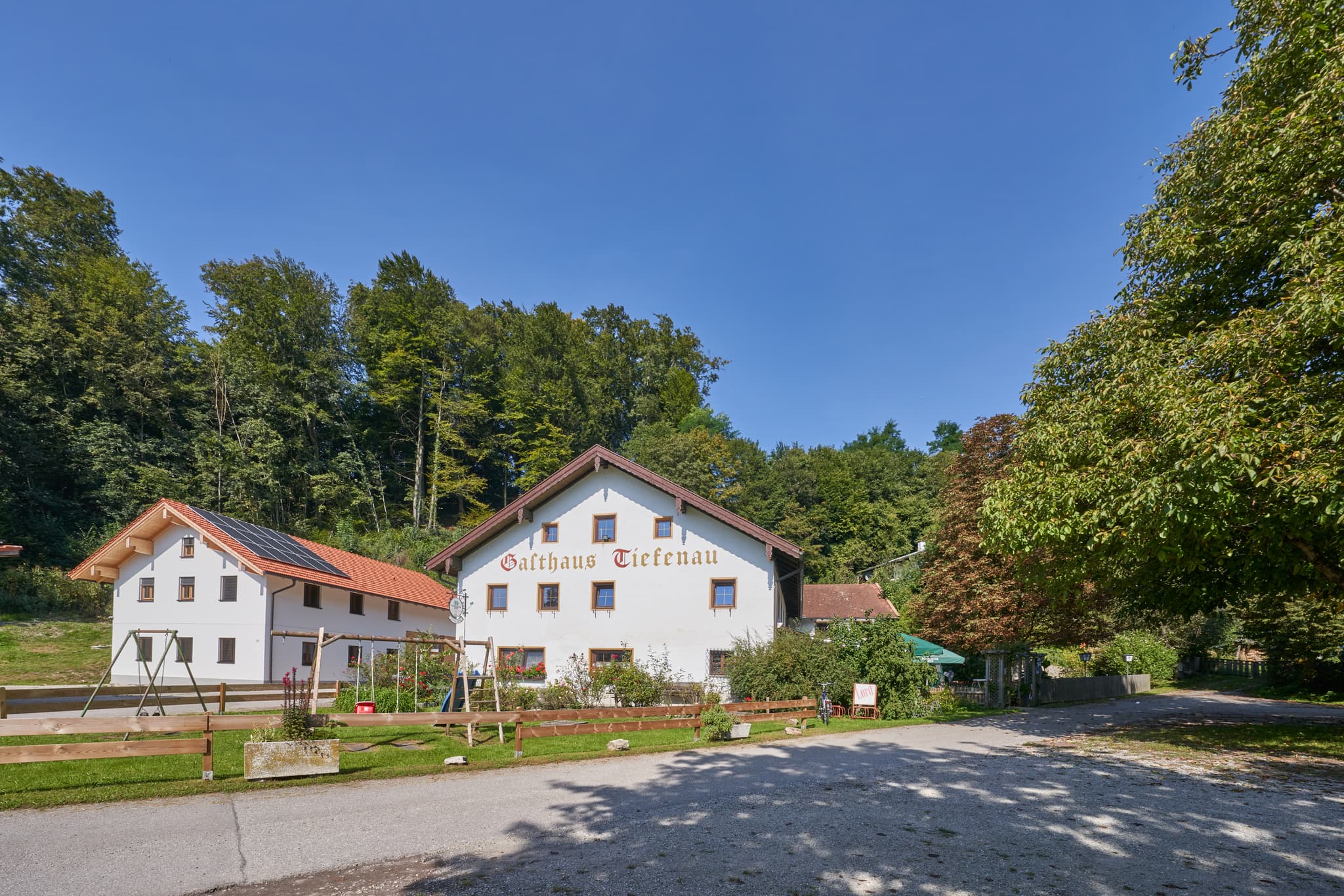 Gasthaus Tiefenau, Tiefenau, Burghausen, Altötting, Oberbayern, Inn-Salzach, Deutschland. Eine ländliche Szenerie mit Gebäude, Bäumen und Parkplatz.