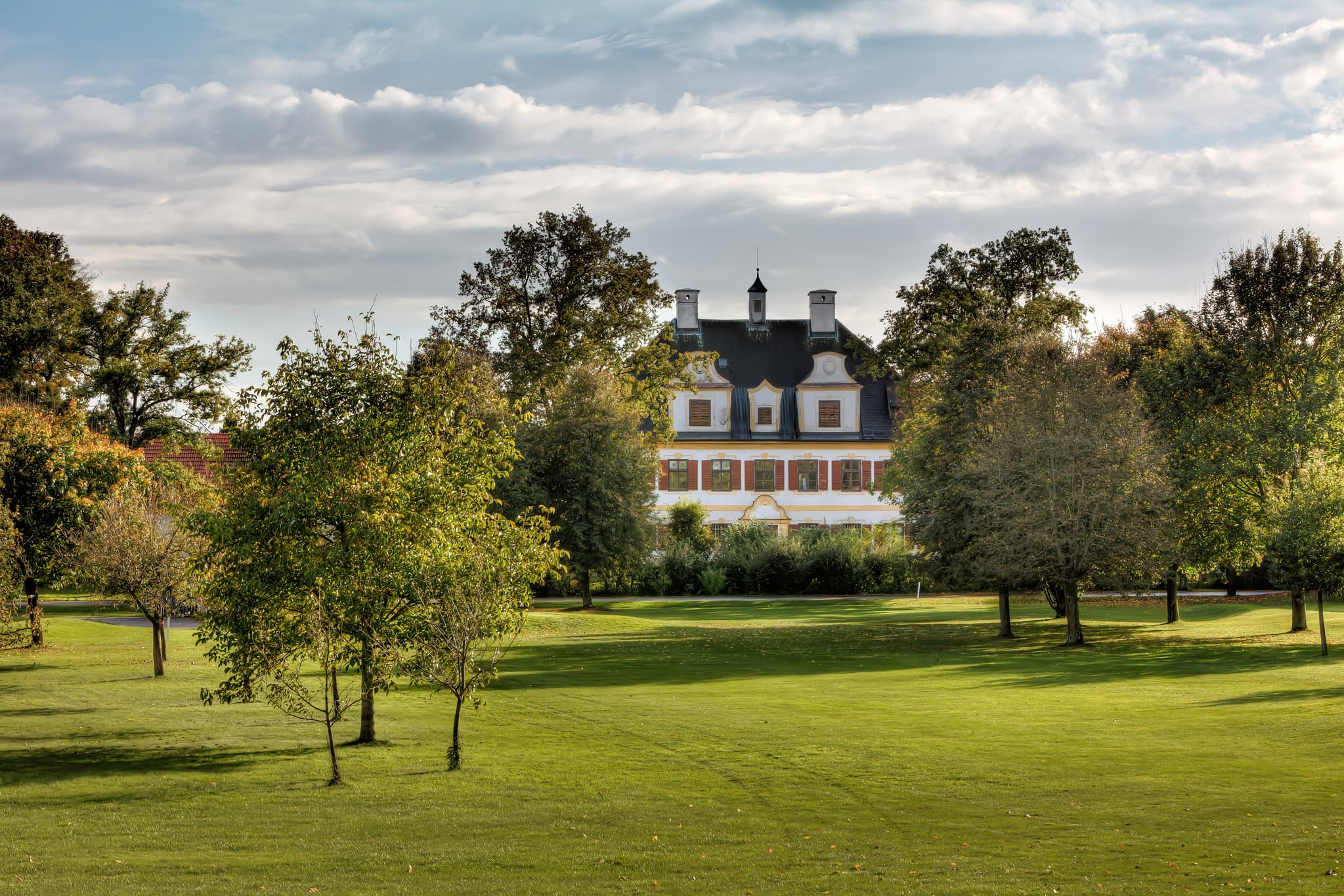 Schloss Piesing in Haiming, Landkreis Altötting, Oberbayern. Gelegen in der Region Inn-Salzach, Deutschland, umgeben von Bäumen und weiten Wiesen.