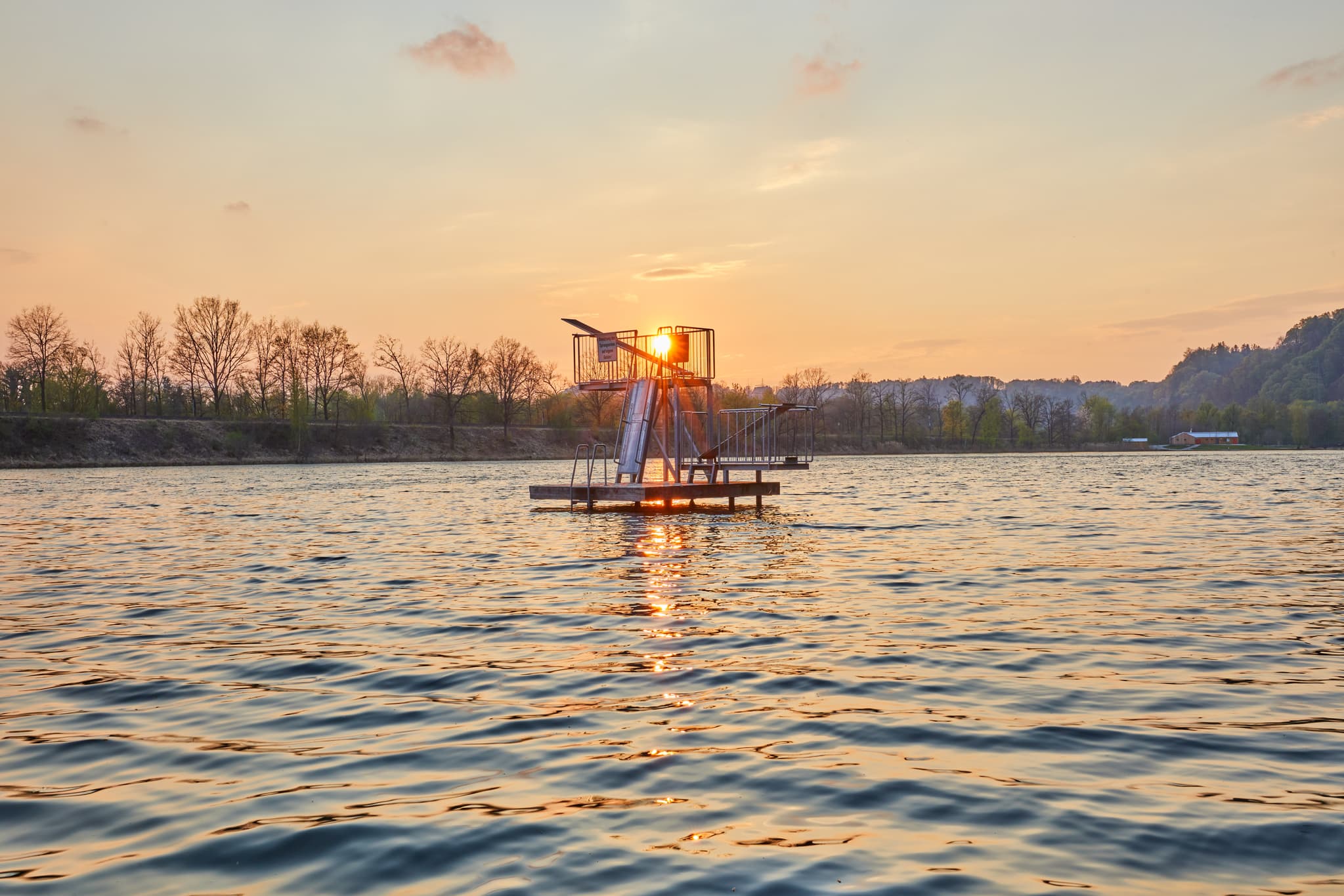 Sonnenuntergang am Marktler Badesee in Oberbayern, Inn-Salzach, Deutschland. Sprunganlage im See. Regionale Sehenswürdigkeit.