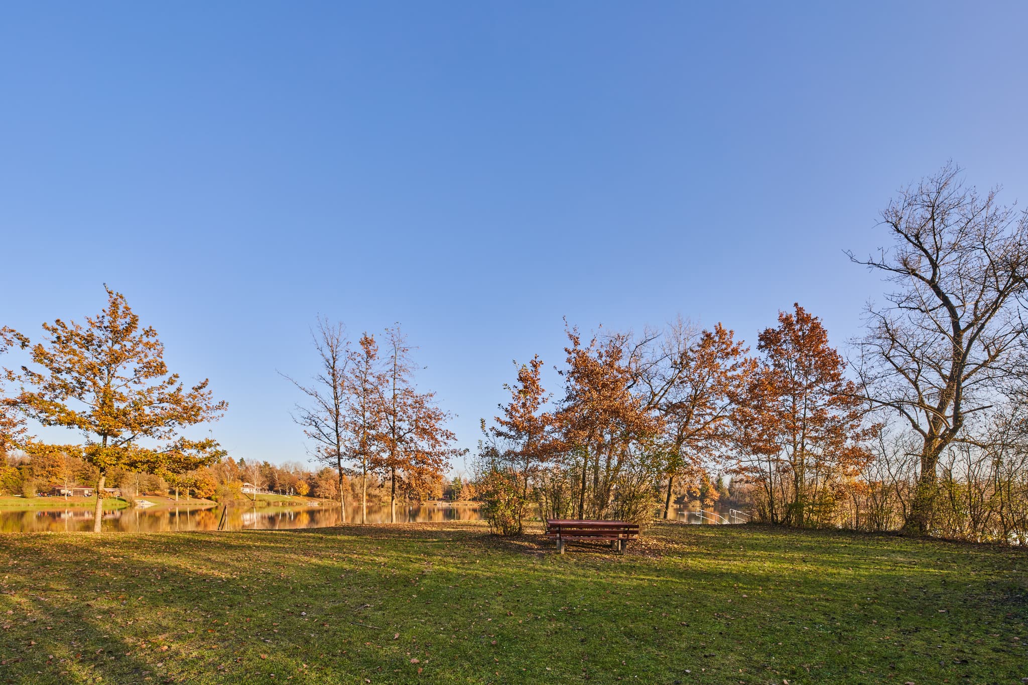 Herbstlicher Waldsee Lago Herbst in Kirchdorf am Inn, Rottal-Inn, Niederbayern. See mit Uferbank, umgeben von B‰umen in Herbstfarben. Natur im Holzland.