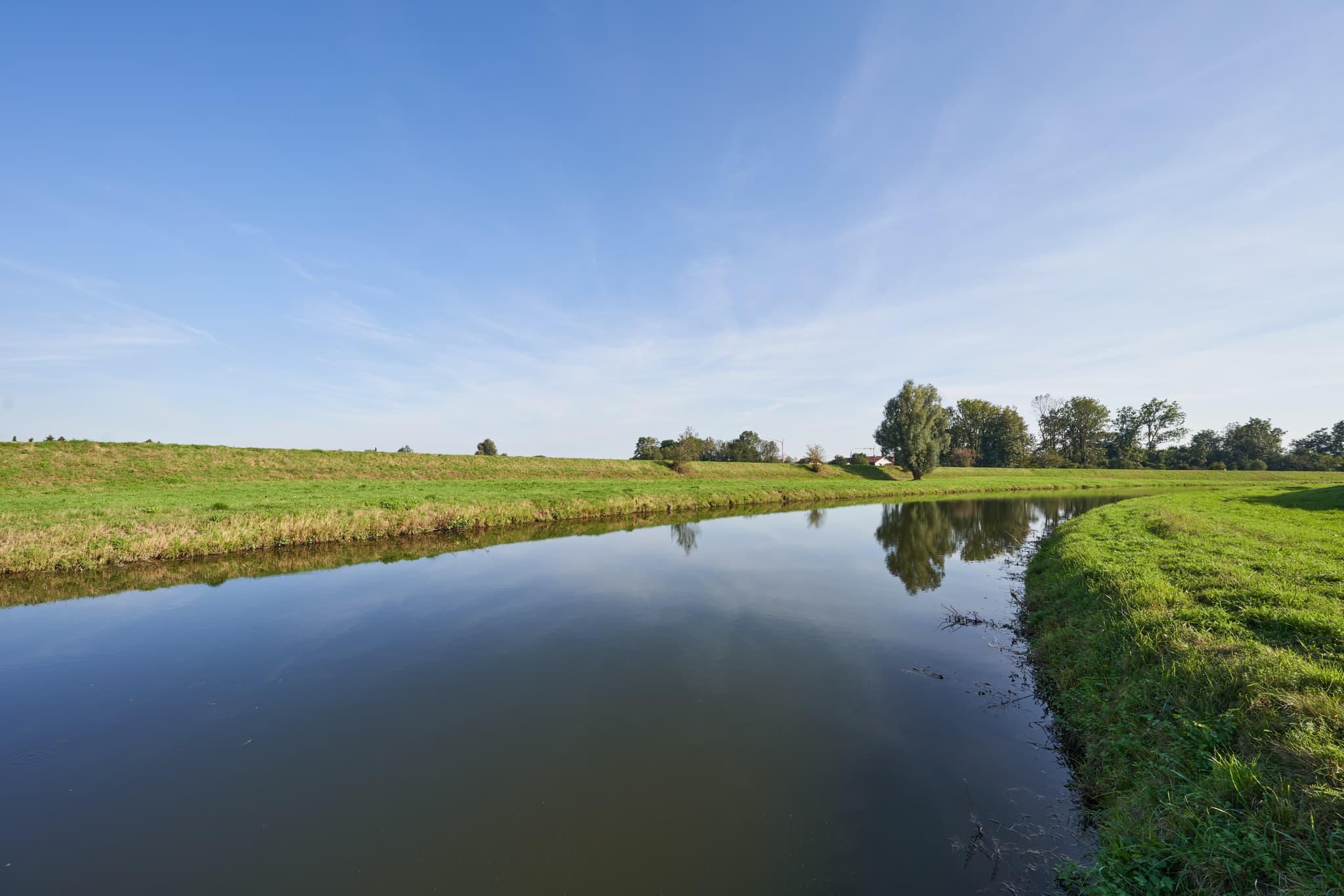 Flusslandschaft mit grünen Ufern und blauem Himmel, fotografiert an der Isen in Kronberg, Winhöring, Altötting, Oberbayern, Inn-Salzach, Deutschland.