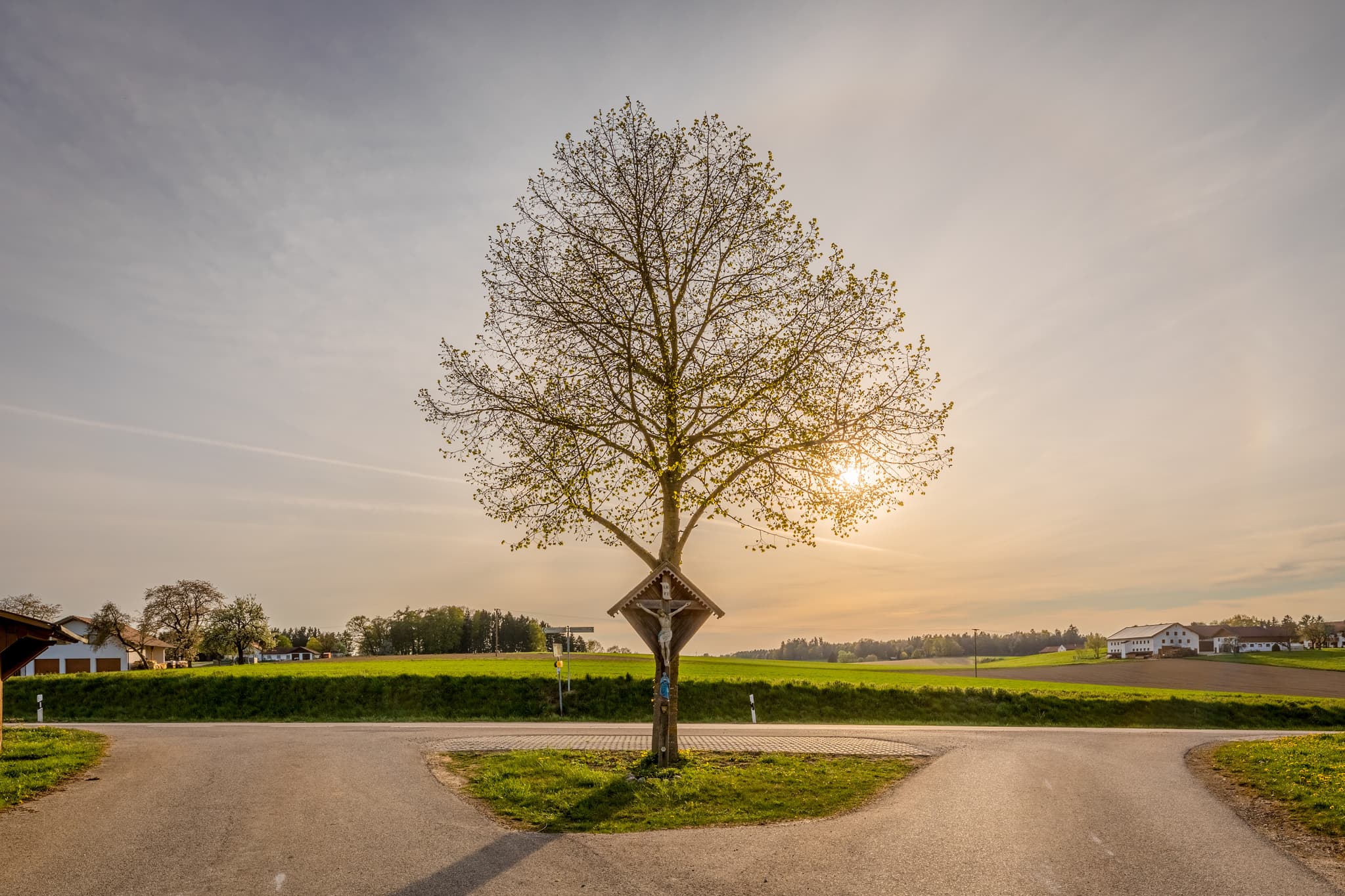 Wegkreuz in Ecking bei Reischach, Landkreis Altötting, Oberbayern, Region Inn-Salzach, Deutschland. Hölzernes Wegkreuz unter einem Baum.