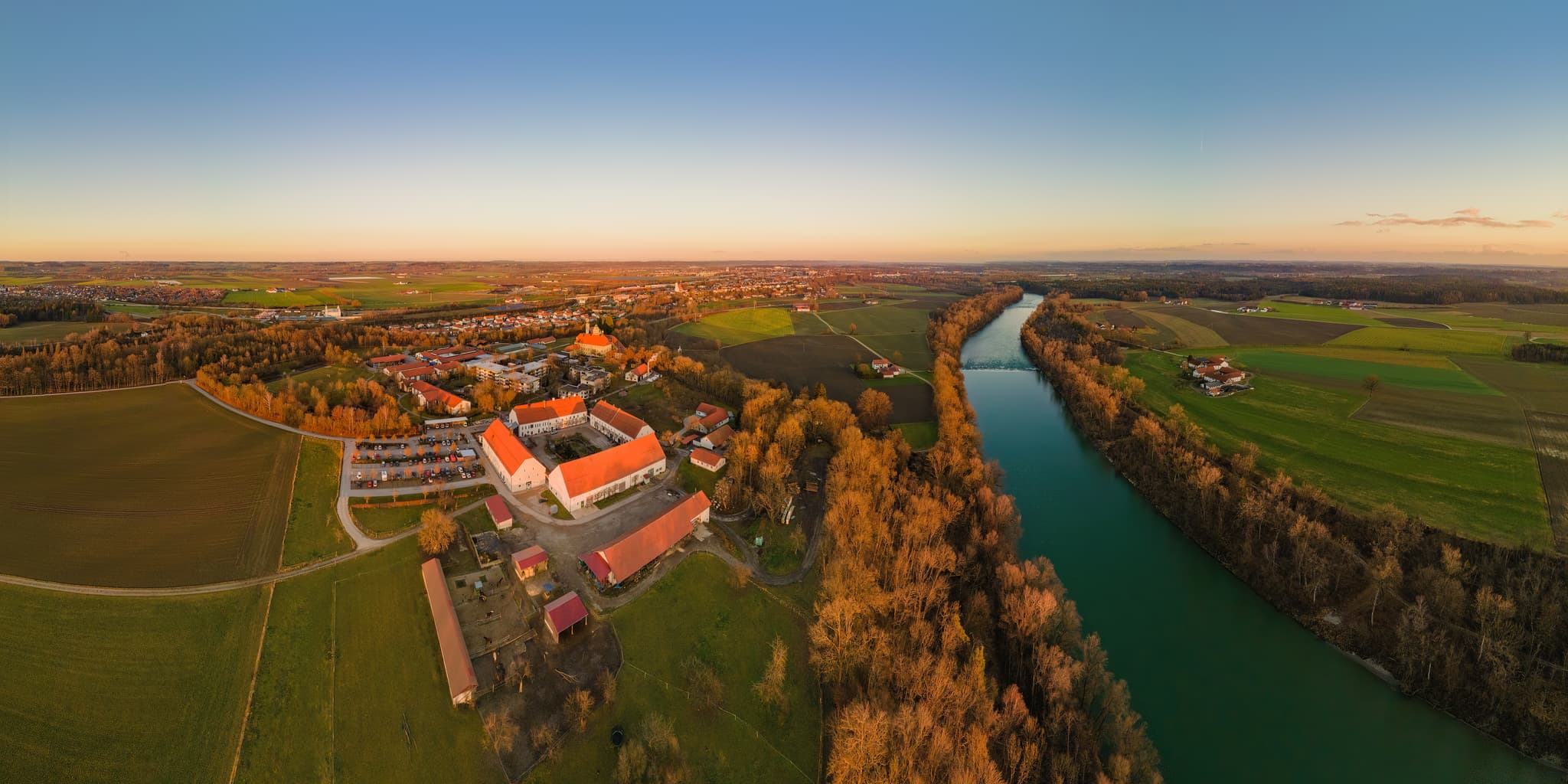 Luftaufnahme von Ecksberg, Mühldorf am Inn, Oberbayern. Das Panorama zeigt Stiftung Ecksberg, Fluss Inn, Felder und Wälder der Inn-Salzach Region im Abendlicht.