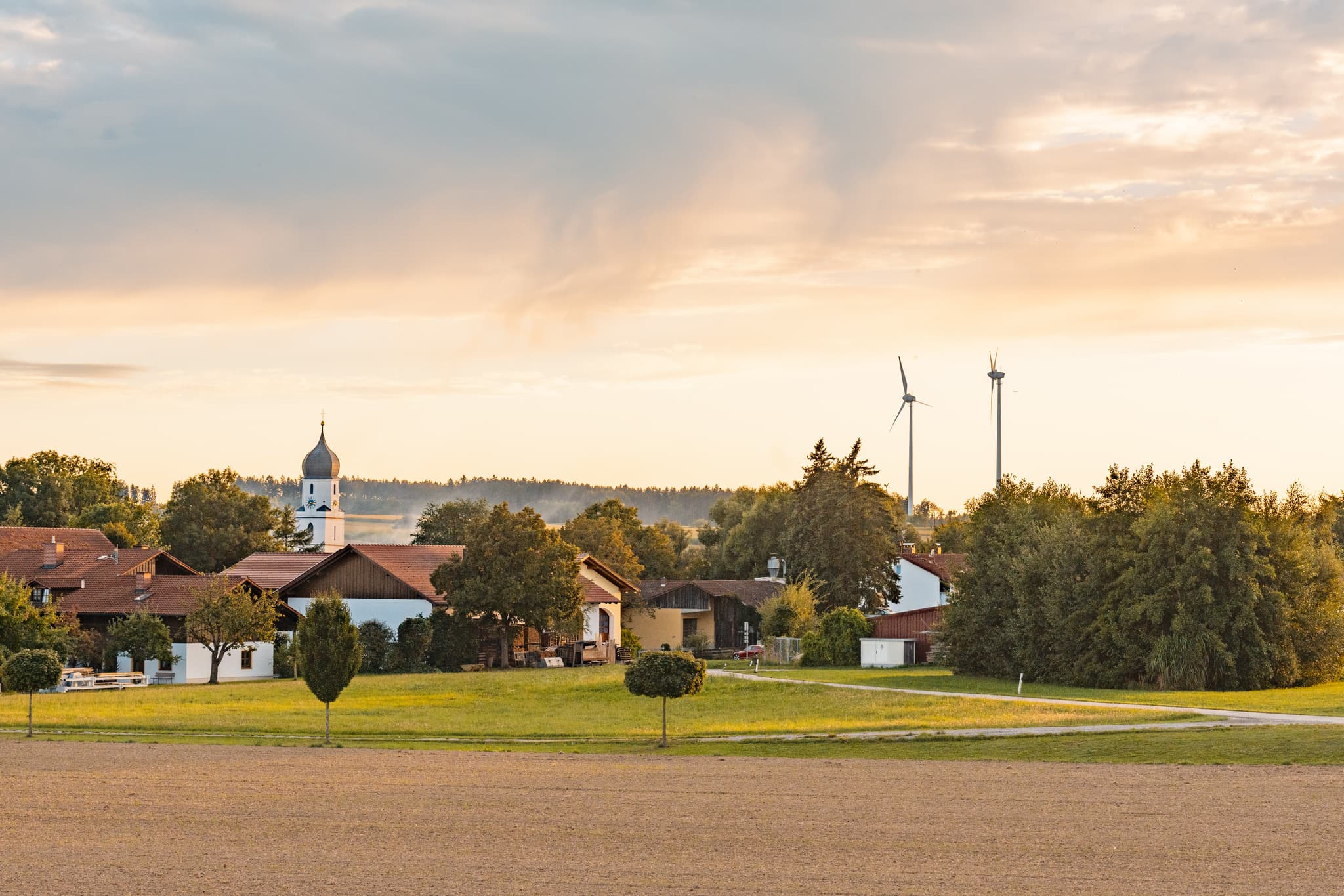 Ortsansicht von Dirnaich, Gangkofen, Landkreis Rottal-Inn, Niederbayern. Ländliche Landschaft im Holzland mit Häusern, Feldern, Windkraftanlagen in Deutschland.