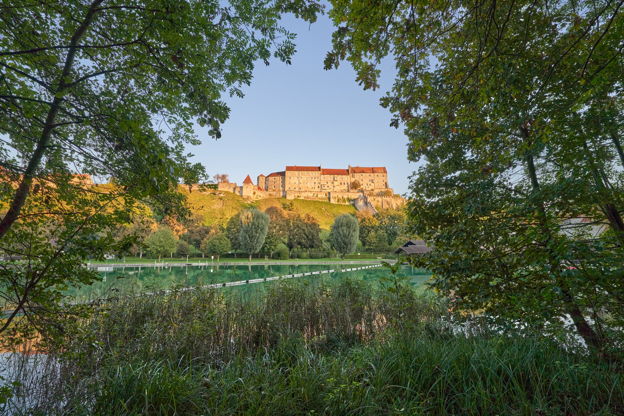 Panorama des Wöhrsees in Burghausen, Landkreis Altötting, Oberbayern, Deutschland, mit der imposanten Burganlage Burghausen im Hintergrund.