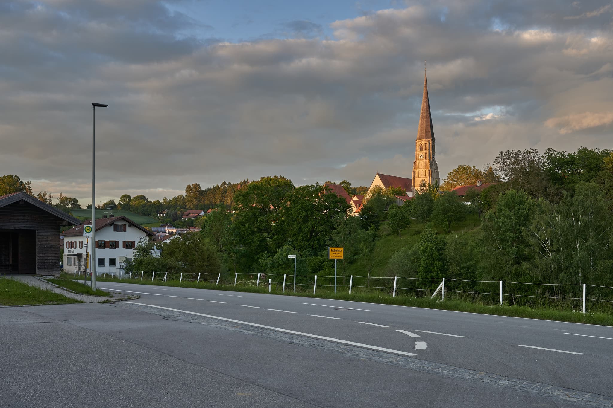 Ortsansicht von Taubenbach im Landkreis Rottal-Inn, Niederbayern, Bayern, Deutschland. Letztes Licht am Kirchturm.
