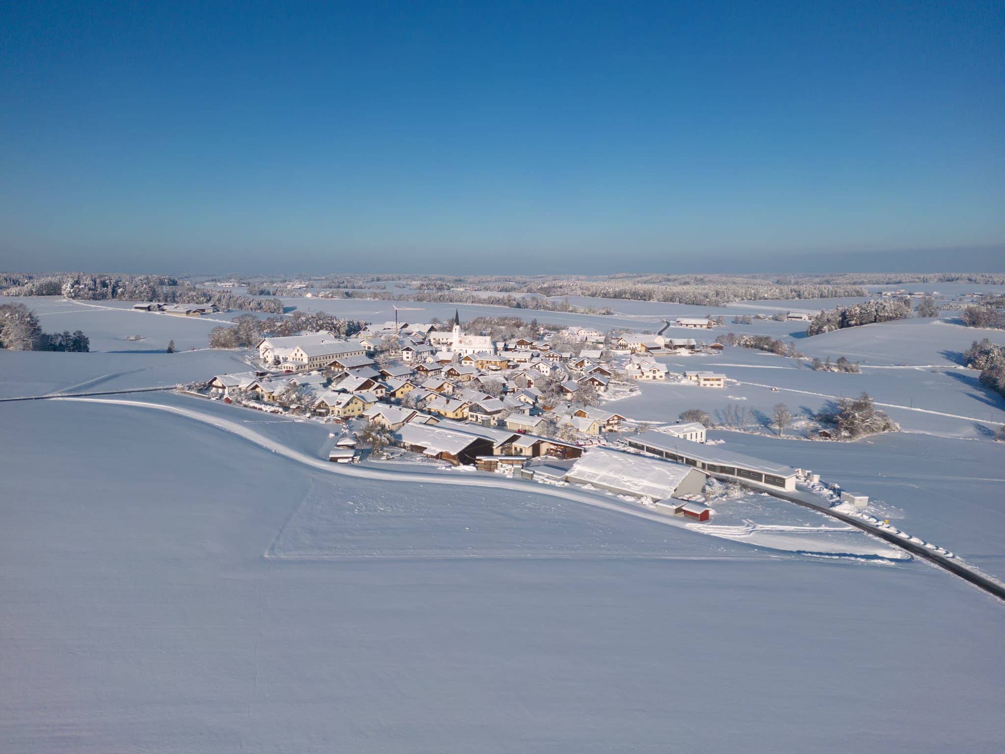 Arbing, Reischach, Altötting, Oberbayern, Deutschland. Die winterliche Landschaft des Holzlands ist tief verschneit. Gebäude, Felder unter Schnee.