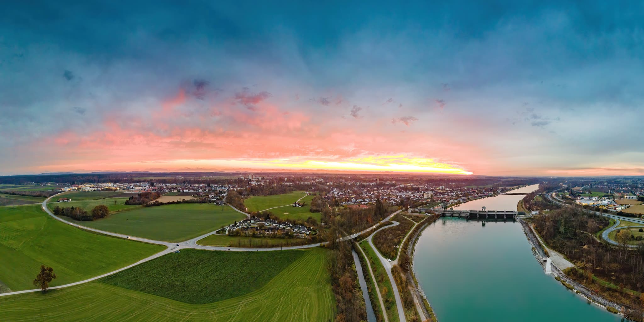 Panoramablick Inn bei Neuötting, Altötting, Oberbayern. Inn-Salzach, Deutschland. Fluss, Felder und Ort unter beeindruckendem Abendhimmel. Ruhige Landschaft.