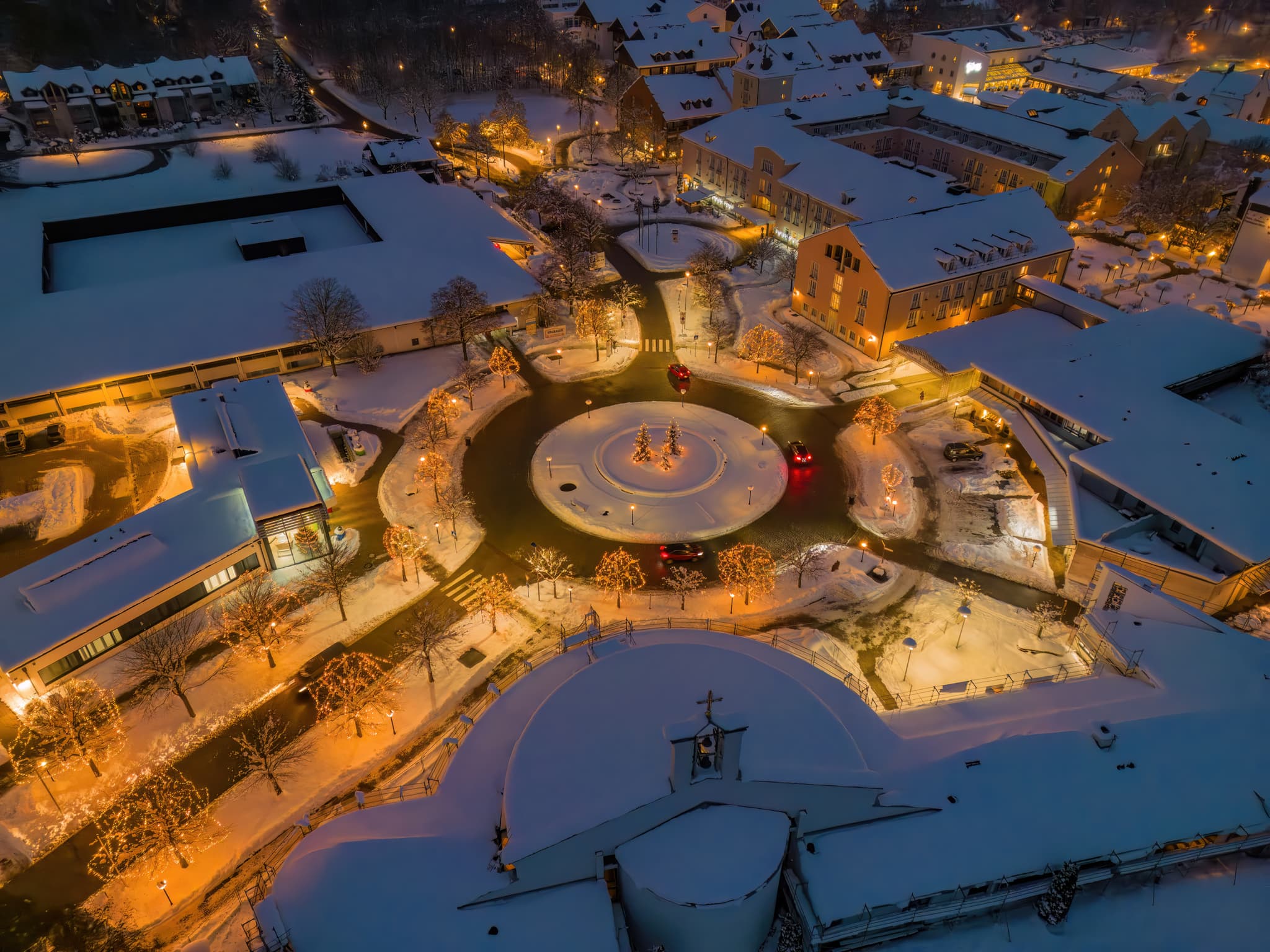 Luftbild des Kreisverkers zur Therme Bad Griesbach in der winterlichen Nacht, Schnee bedeckt Gebäude und Gelände, Landkreis Passau, Niederbayern, Donau-Wald.