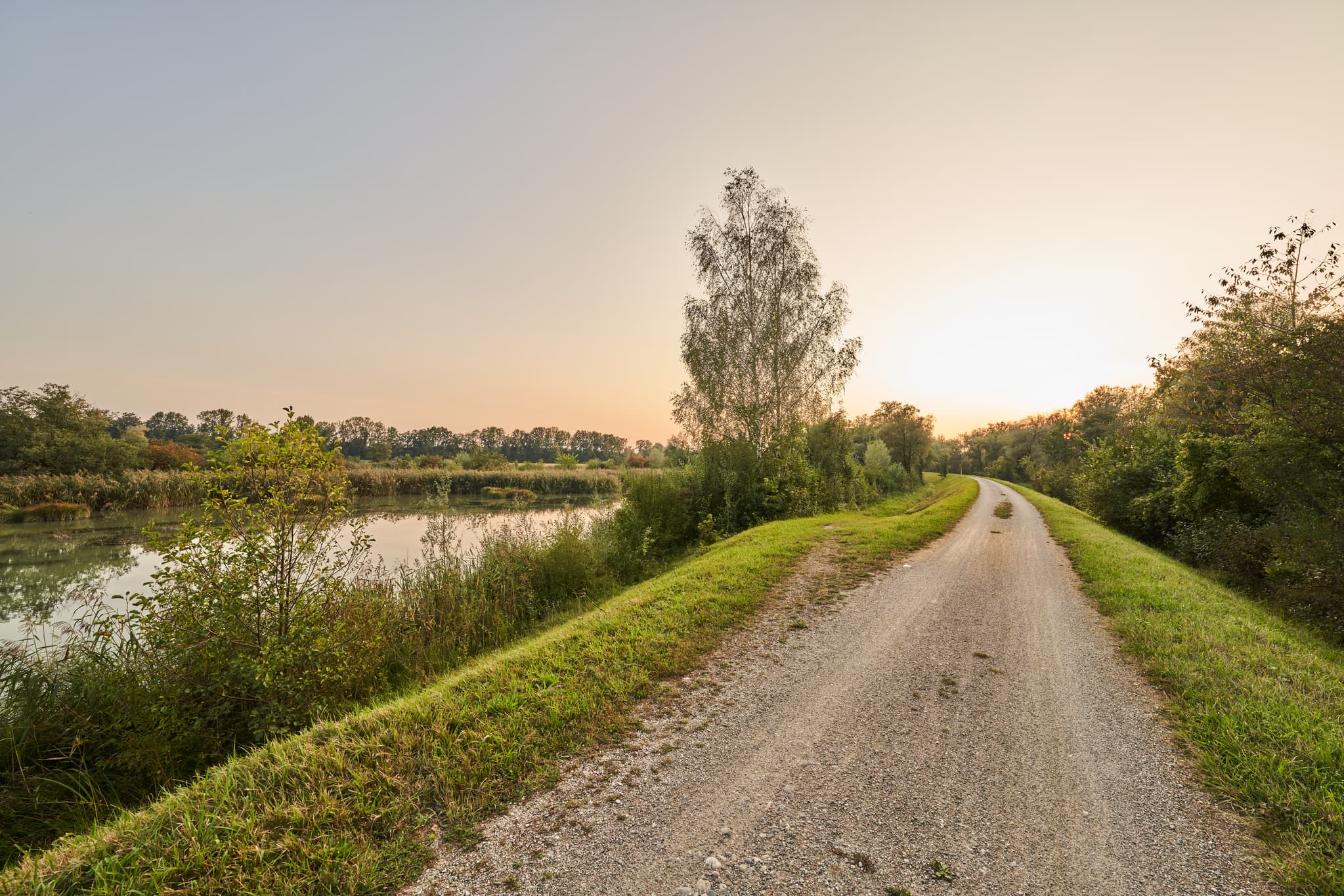 Ein idyllischer Weg führt am Wasser entlang in Altötting, Landkreis Altötting, Oberbayern, Inn-Salzach, Deutschland. Die ruhige Natur lädt zur Erholung ein.
