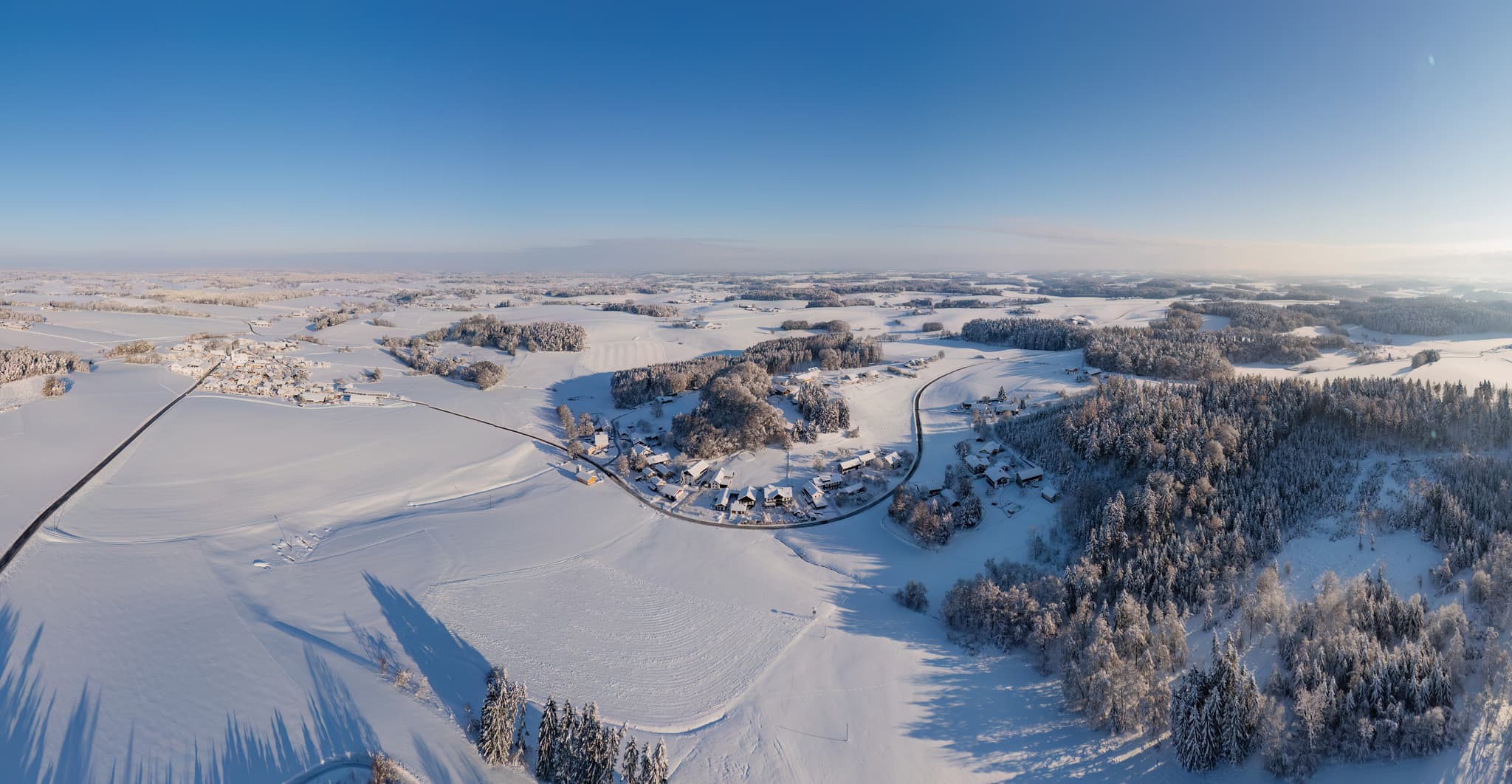 Luftbild der Winterlandschaft um Arbing Waldberg, Reischach, Landkreis Altötting, Oberbayern. Verschneite Felder, Wälder und kleine Siedlungen.