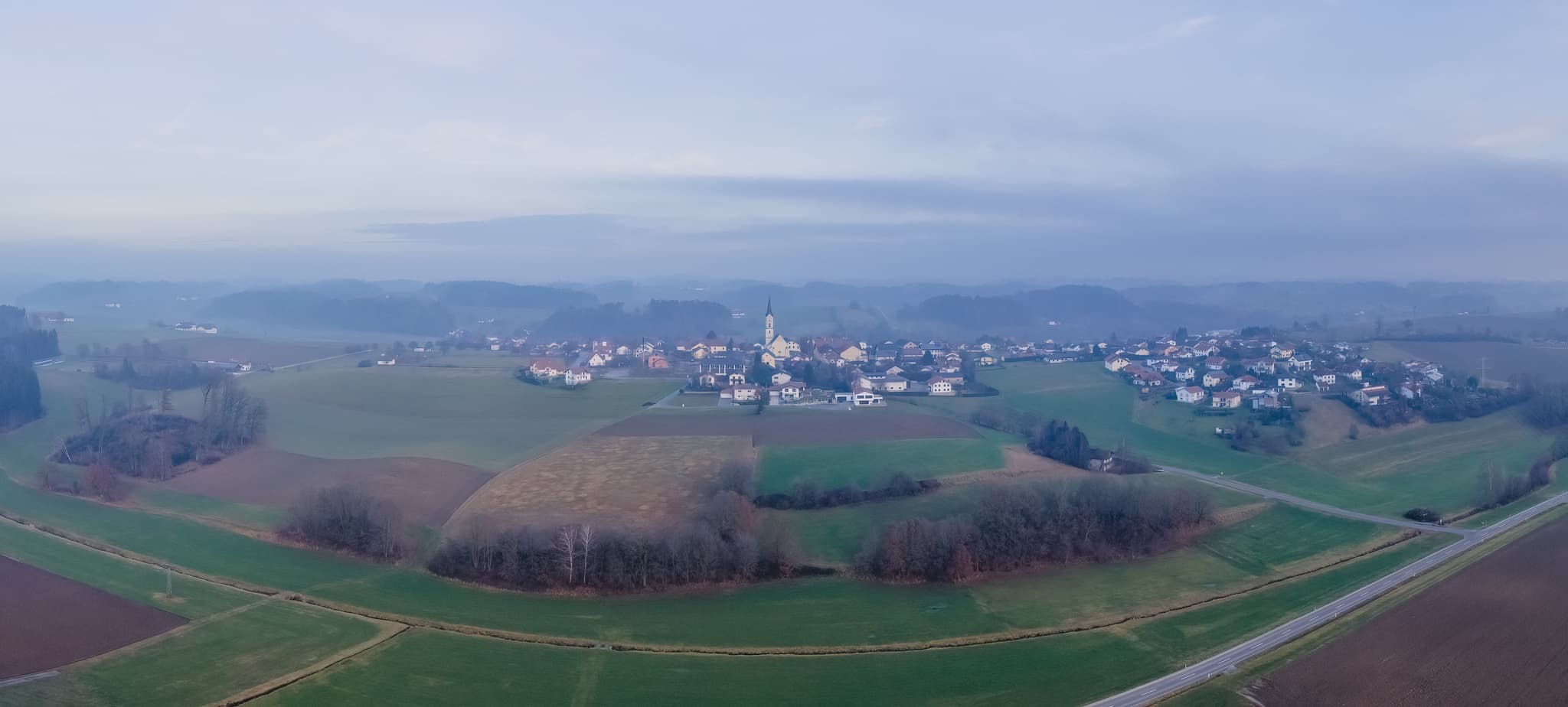 Panoramablick auf Pleiskirchen im Landkreis Altötting, Oberbayern, Deutschland. Die Ortschaft liegt in der Inn-Salzach Region, umgeben von Feldern und Wäldern.