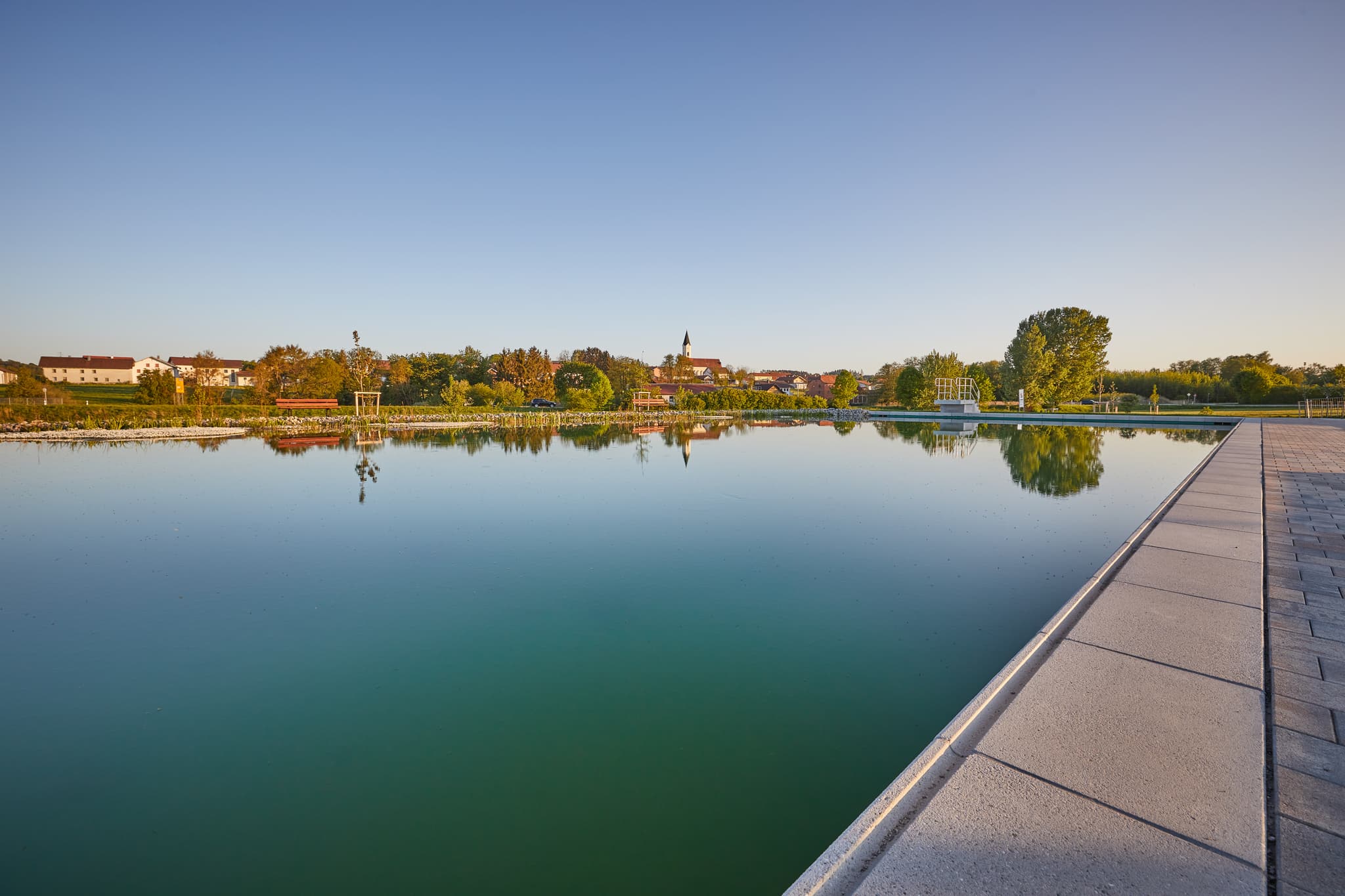 Naturbad am Wassergarten in Mitterskirchen, Landkreis Rottal-Inn, Niederbayern, Bayern, Deutschland. Idyllisches Freibad mit Blick auf die Kirche.