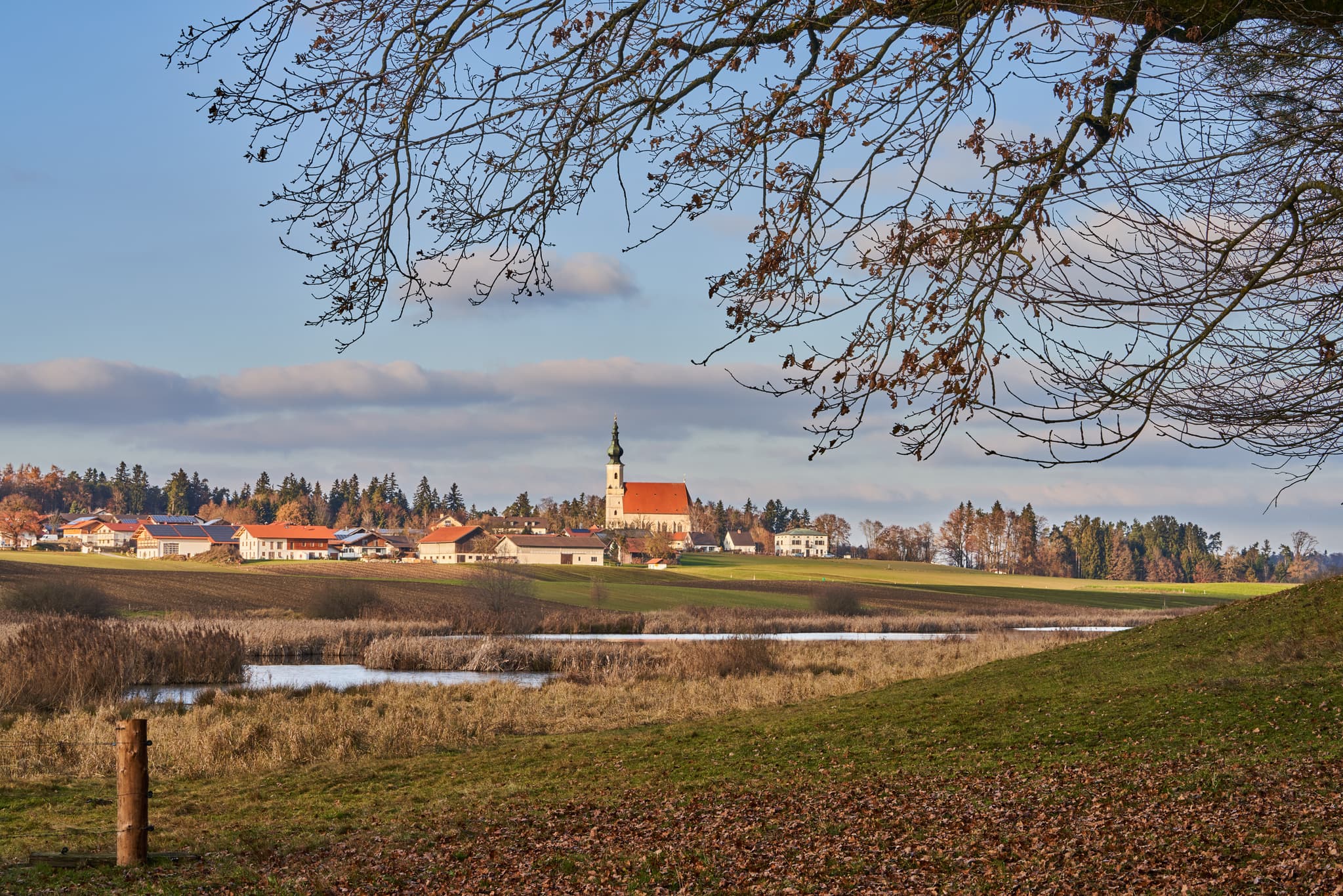 Idyllische Herbstlandschaft am Astner Moos bei Tittmoning in Oberbayern, Inn-Salzach, Deutschland. Ein malerischer Ausblick auf die Landschaft und die Kirche.