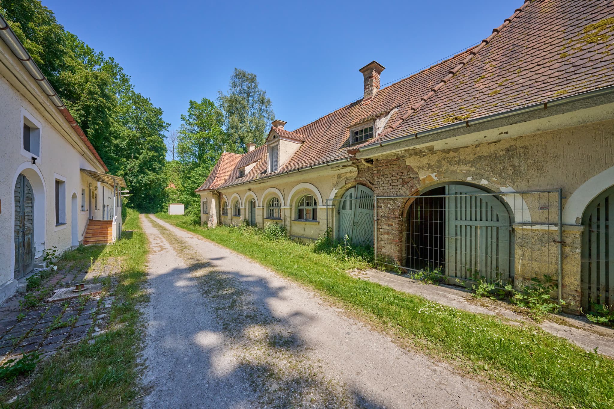 Ansicht der historischen Alten Wäscherei in Ecksberg, Mühldorf. Gebäude an Feldweg, grüne Natur, klarer Himmel.