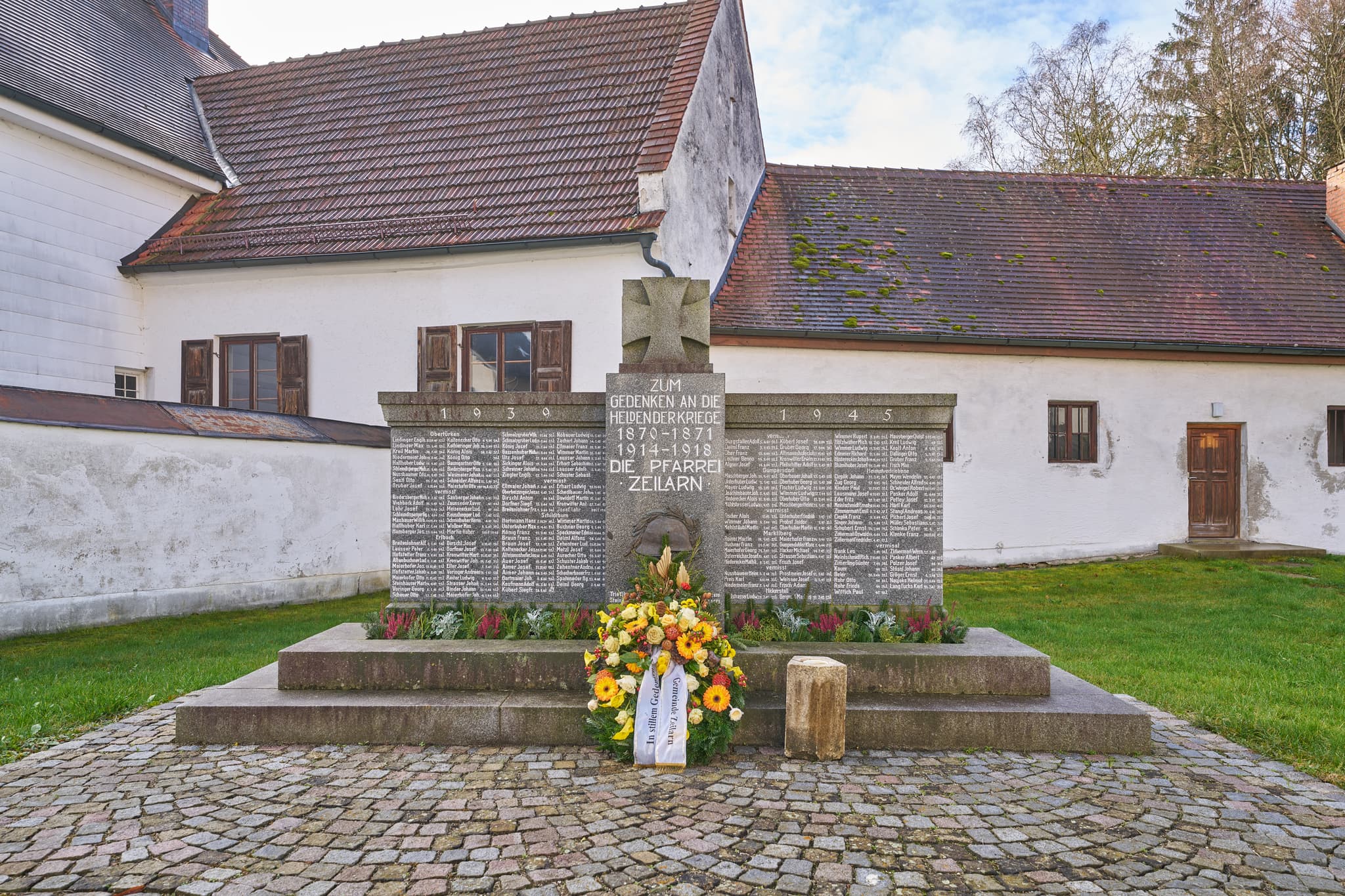 Kriegerdenkmal der Pfarrkirche St. Martinus in Zeilarn, Rottal-Inn, Niederbayern. Denkmal auf gepflastertem Vorplatz mit Kranz.