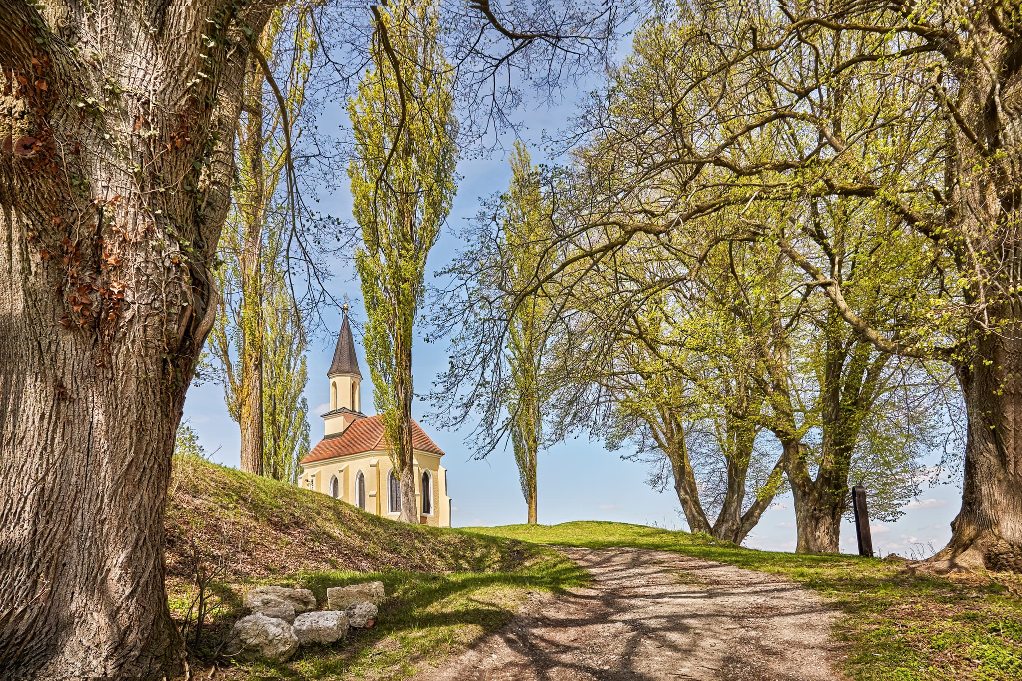 St.-Georgs-Kirchlein auf dem Schlossberg in Kraiburg, Mühldorf am Inn, Oberbayern, Inn-Salzach, Deutschland. Kleine Kirche auf grünem Hügel, umrahmt von Bäumen.