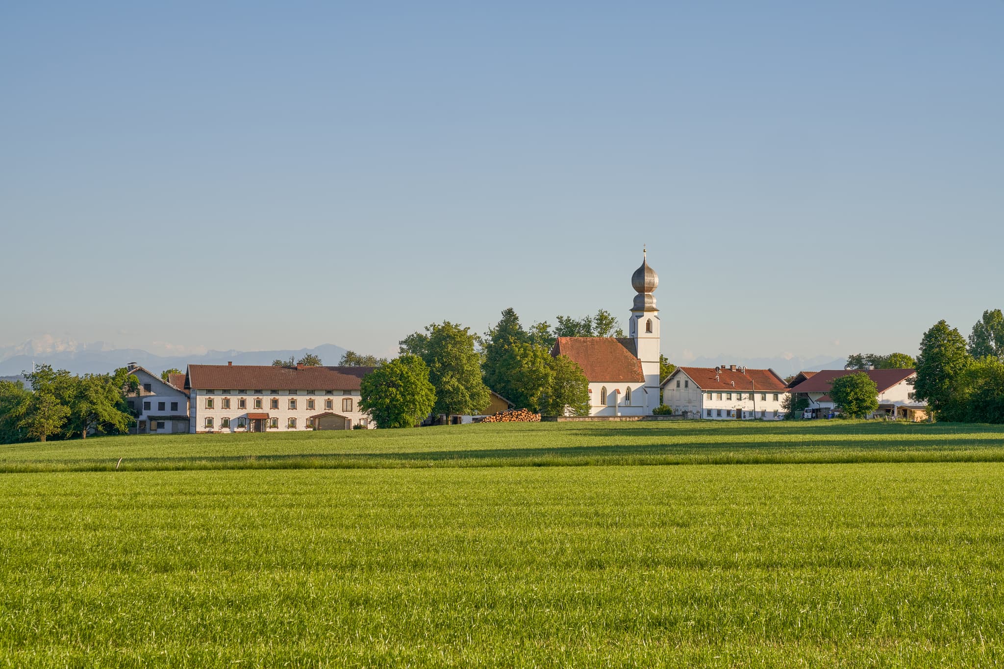 Idyllisches Landschaftsbild von Kirchweidach bei Neukirchen an der Alz in Oberbayern, Inn-Salzach, Deutschland. Kirche und die umliegenden Gebäude.