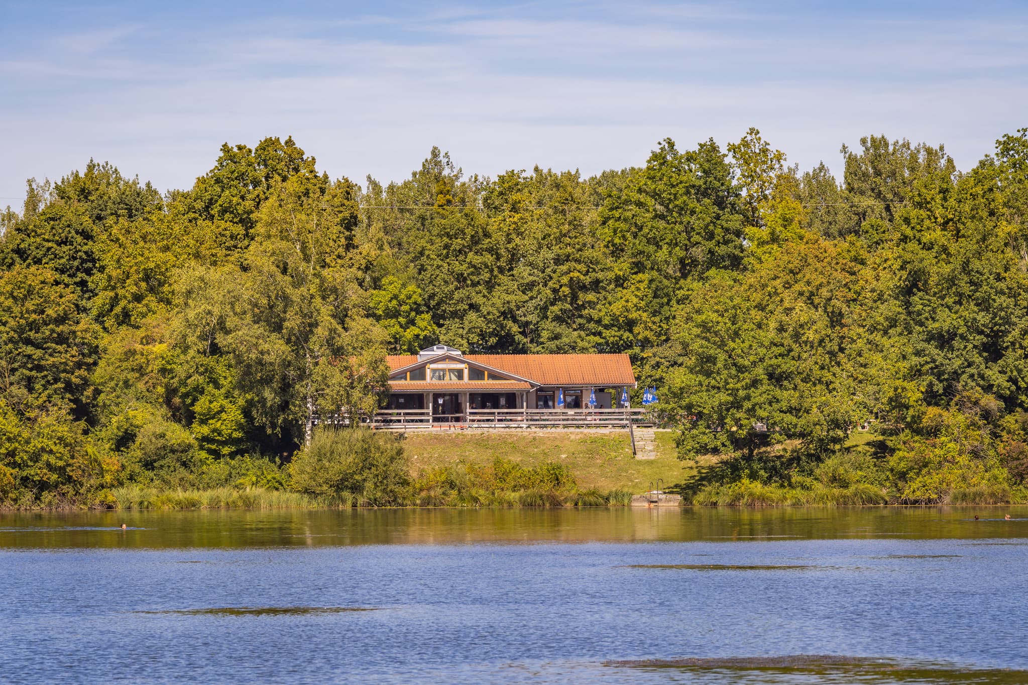 Waldsee Lago Sommer und Badesee Simbach in Kirchdorf am Inn, Rottal-Inn, Niederbayern. Ein Gebäude liegt idyllisch am bewaldeten Ufer. Bäderdreieck, Deutschland