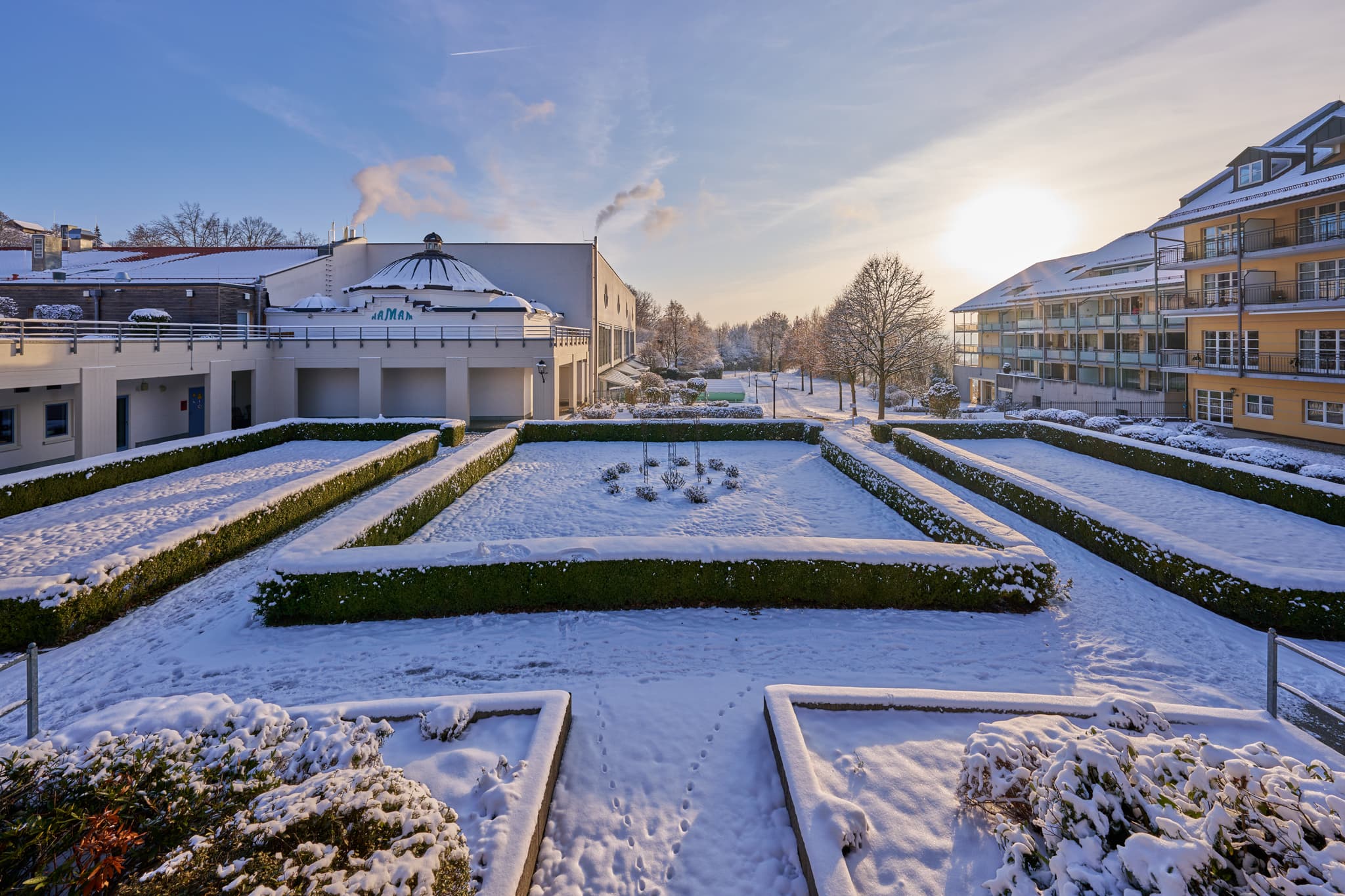 Ein winterlicher Blick auf den Kurplatz in Bad Griesbach im Rottal, Landkreis Passau, Niederbayern. Schnee bedeckt die Anlage unter strahlendem Sonnenschein.