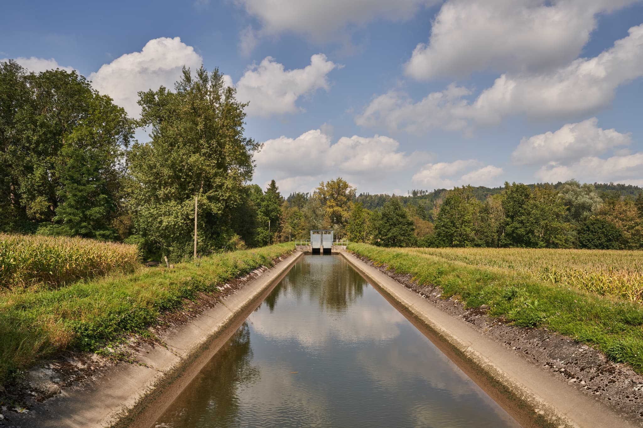 Blick auf den Isenkanal, umgeben von Feldern und Bäumen, bei Winhöring im Landkreis Altötting, Oberbayern, Region Inn-Salzach, Deutschland.
