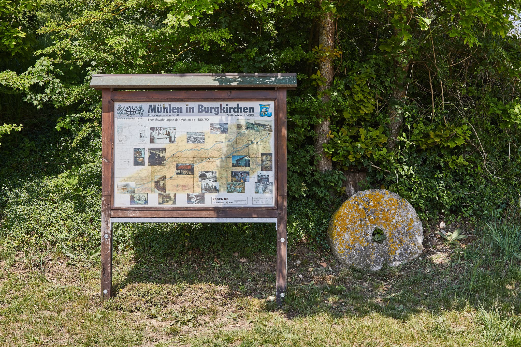 Historisches Mühlrad und Infotafel zum Thema Mühlen am Mühlenweg in Burgkirchen, Landkreis Altötting, Oberbayern, Deutschland. Region Inn-Salzach.