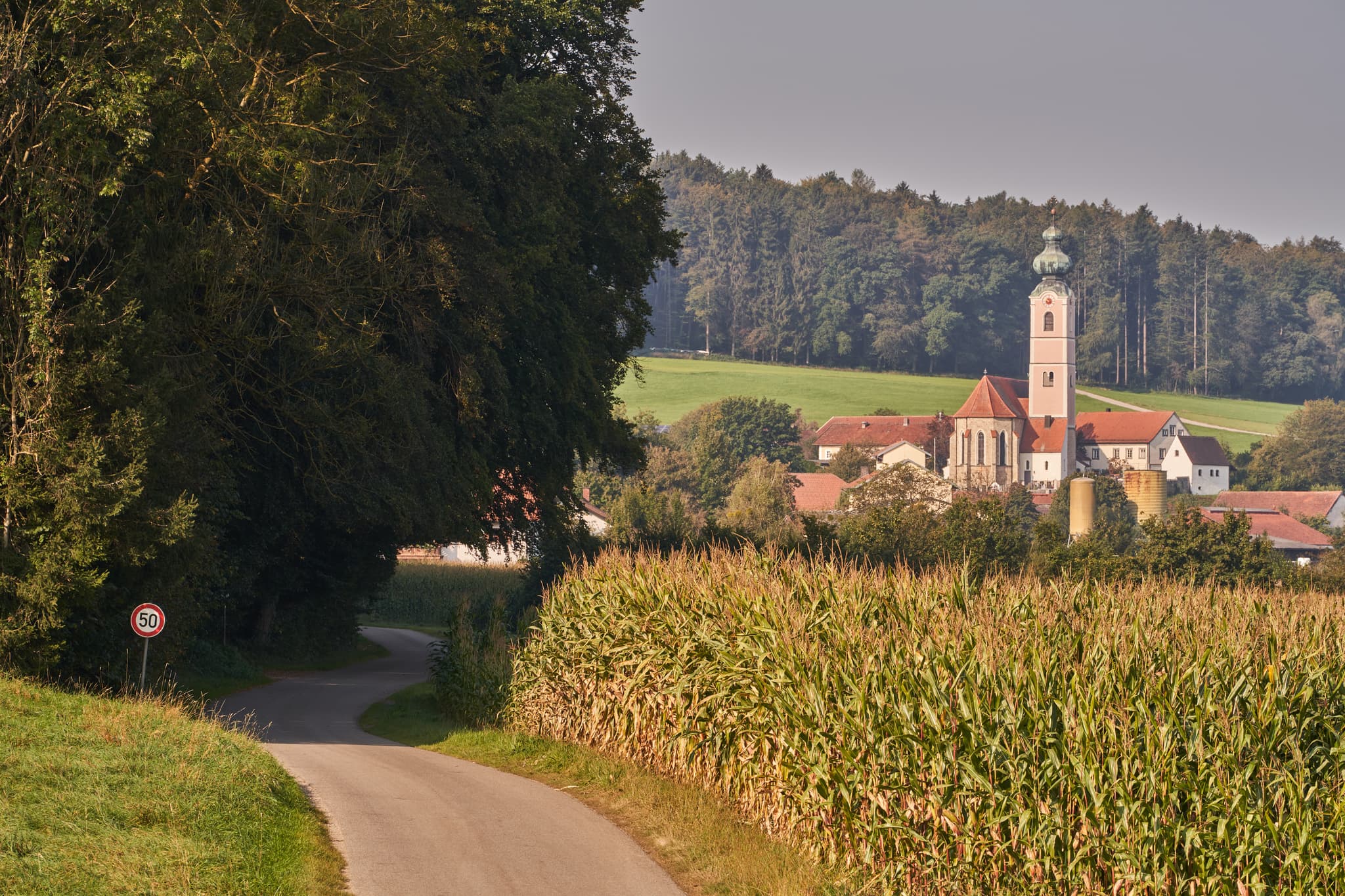 Pilgerweg durch Felder bei Badhöring, einem Ortsteil von Mehring. Blick auf das Dorf mit Kirche in Altötting, Oberbayern, Region Inn-Salzach, Deutschland.