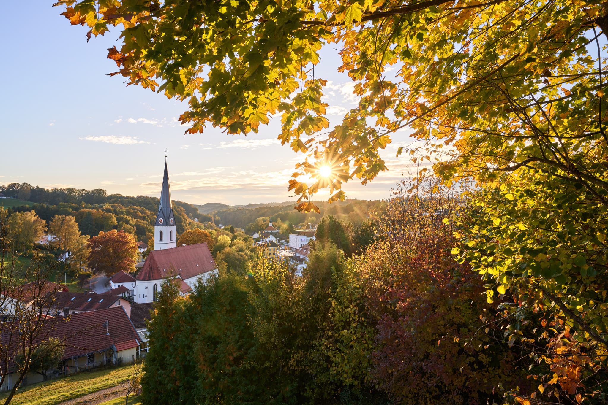 Aussicht am Zoglerberg im Herbst, Reischach, Landkreis Altötting, Oberbayern. Mit malerischer Kirche, bunten Bäumen.