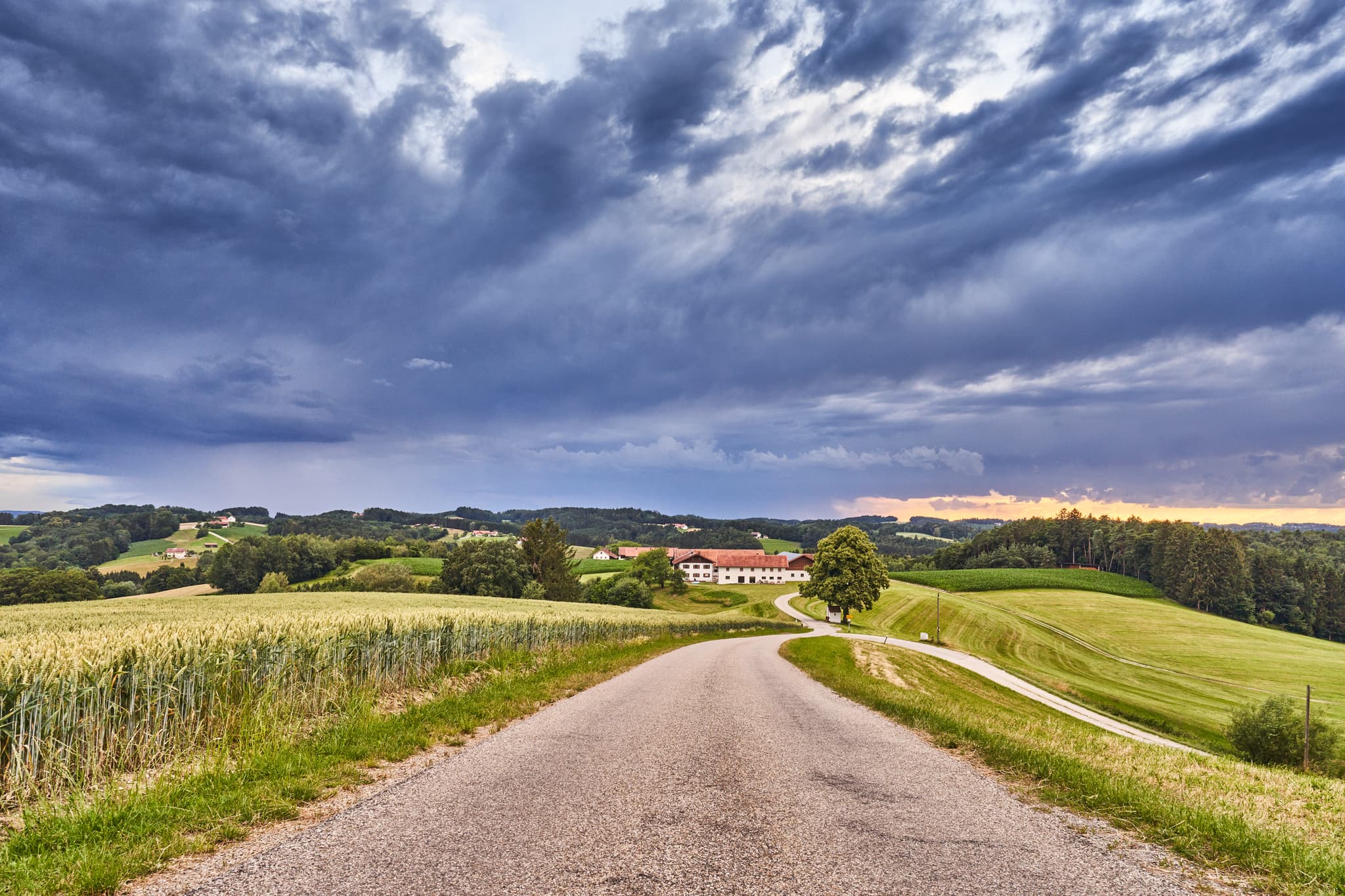 Friesing bei Reischach, Altötting, Oberbayern, Inn-Salzach, Deutschland. Eine ländliche Hügellandschaft mit Feldern und Landstraßen unter dramatischem Himmel.