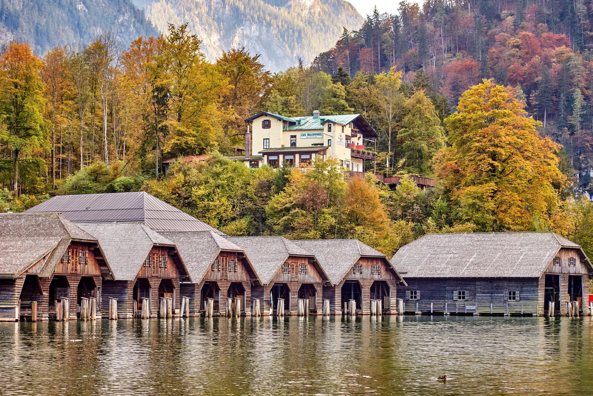 Bootshäuser am Königssee, Schönau. Umgeben von herbstlicher Natur und Bergen im Berchtesgadener Land, Oberbayern. Region Berchtesgadener Alpen, Deutschland.