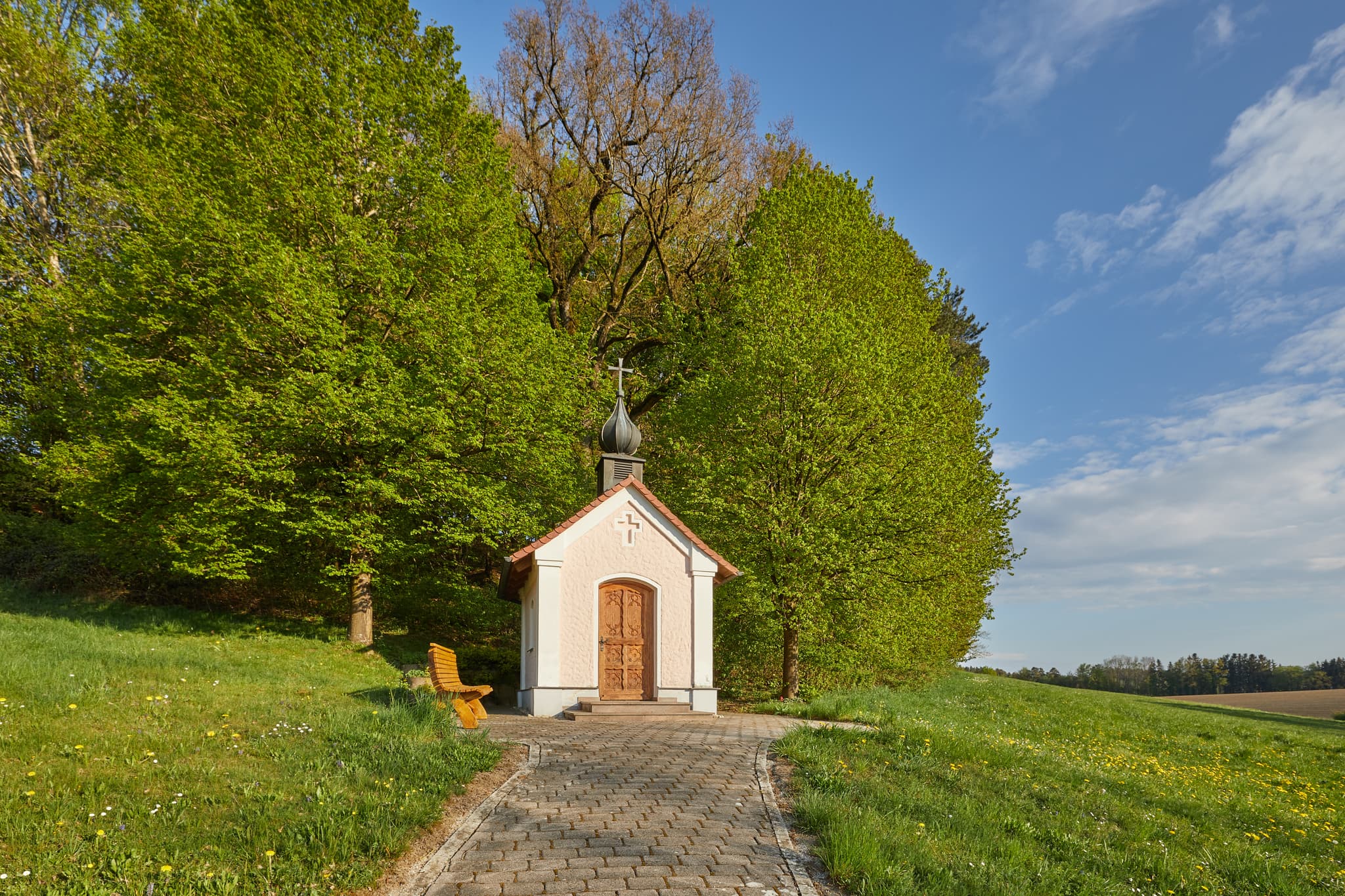 Hickerstall Kapelle in Wurmannsquick, Rottal-Inn, Niederbayern. Eine kleine Kapelle auf einer grünen Anhöhe, umgeben von Wiesen und Bäumen im Holzland.