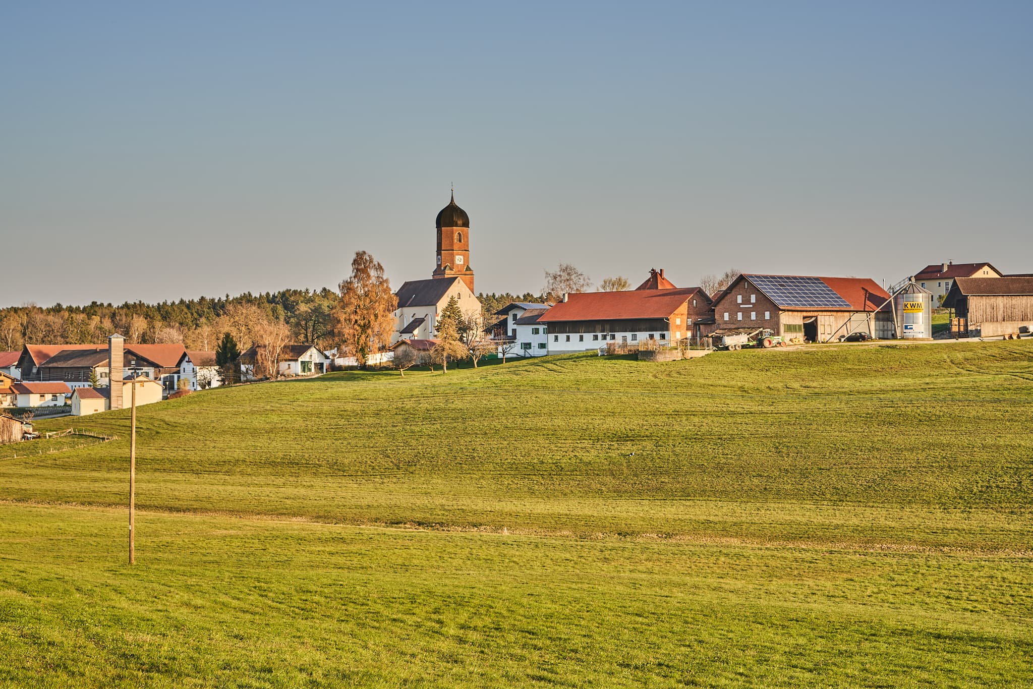 Kirche und Bauernhöfe mit Solaranlagen in Martinskirchen, Wurmannsquick, Landkreis Rottal-Inn, Niederbayern. Typische Landschaft des Holzlands, Deutschland.